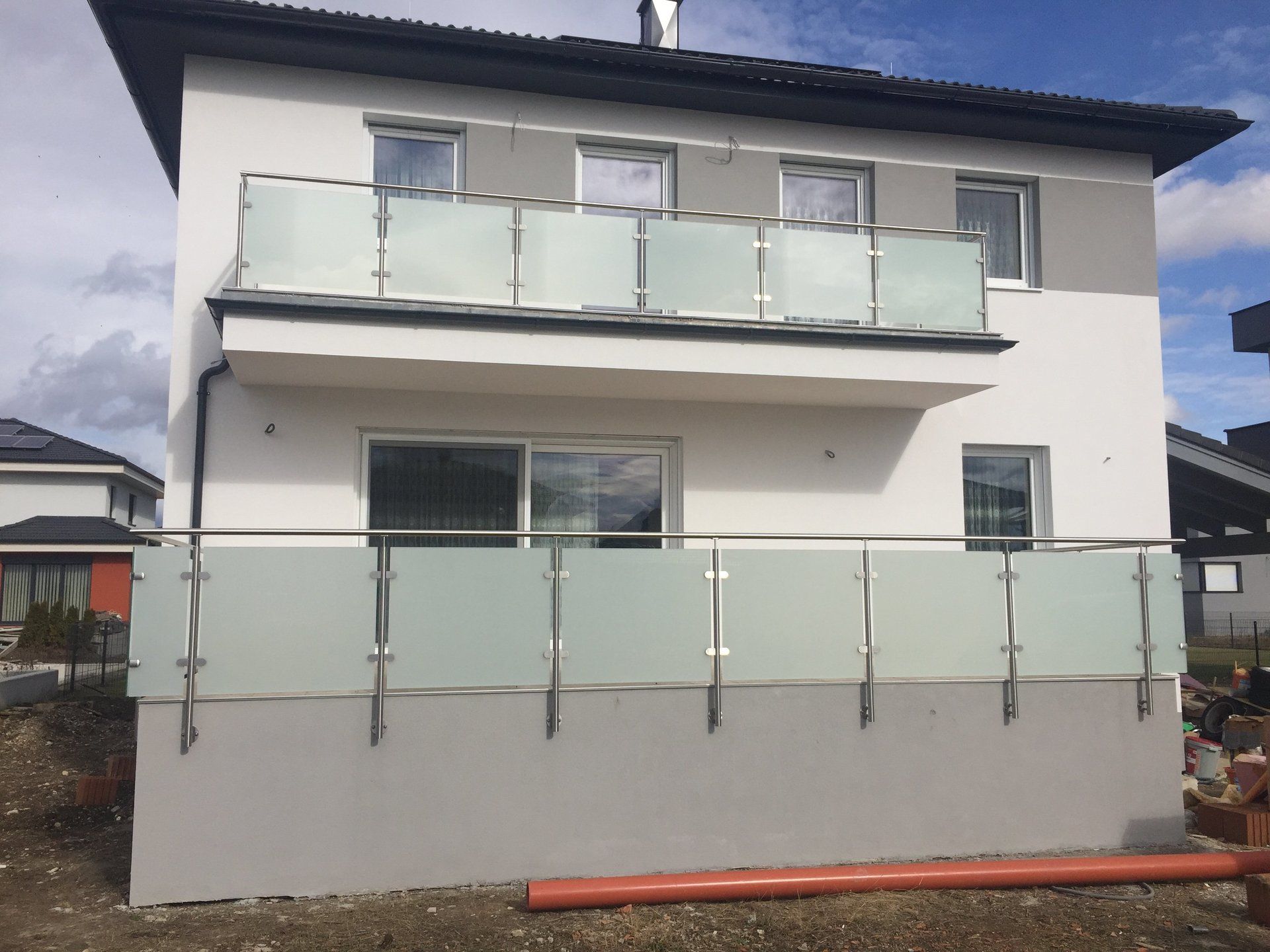 Ein weißes Haus mit Balkon und Edelstahlgeländer