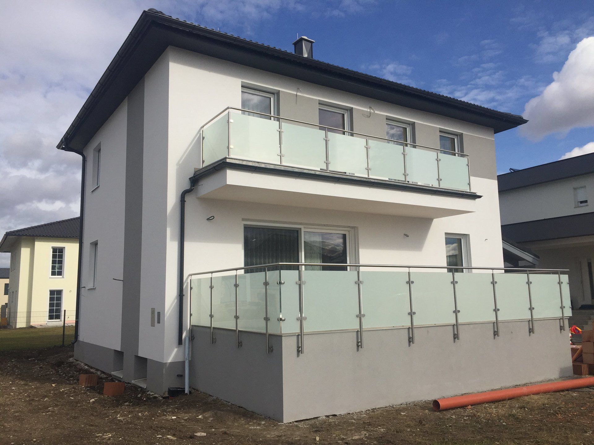 Ein weißes Haus mit Balkon und Edelstahlgeländer