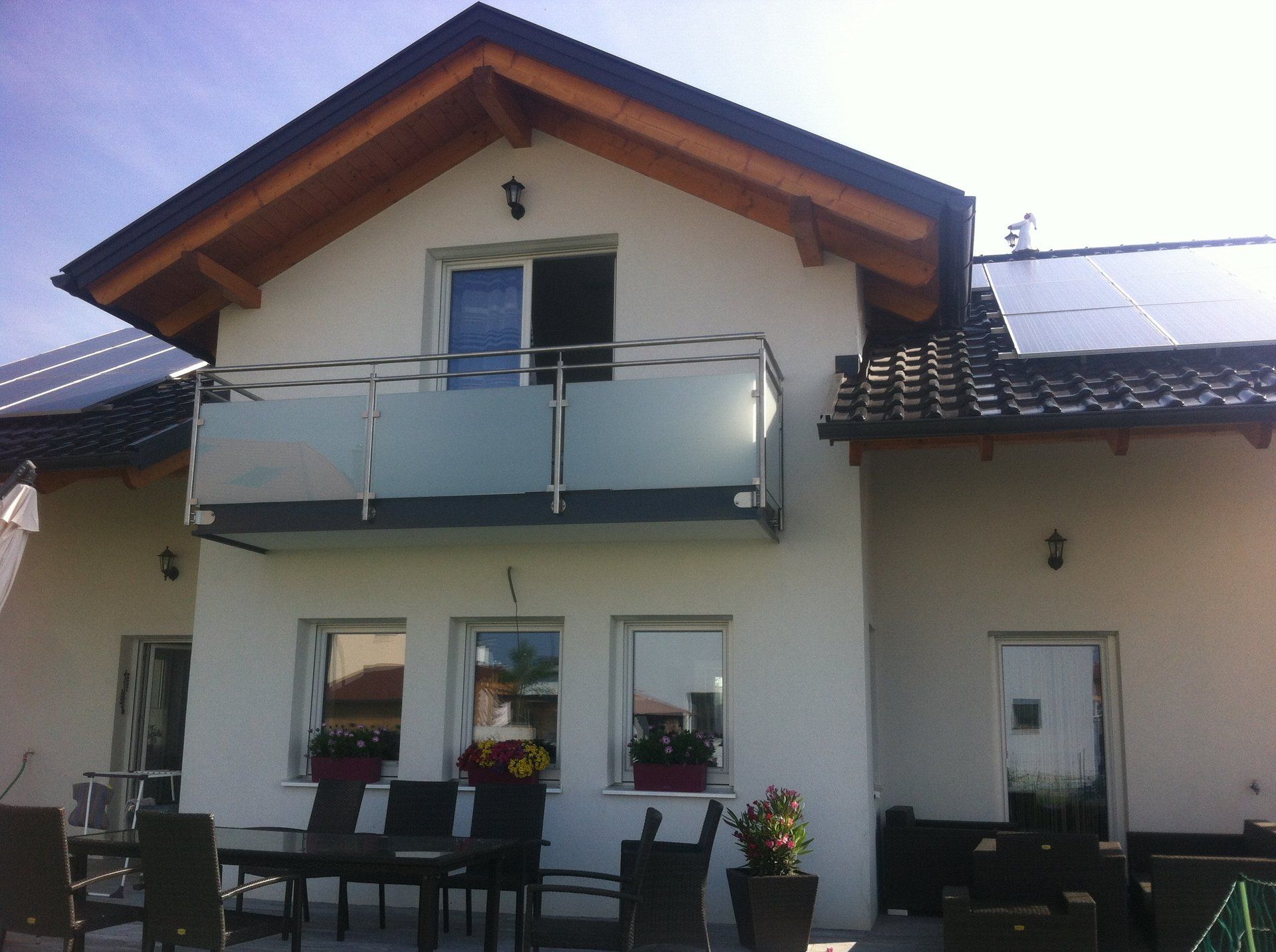 Ein weißes Haus mit Balkon und Sonnenkollektoren auf dem Dach