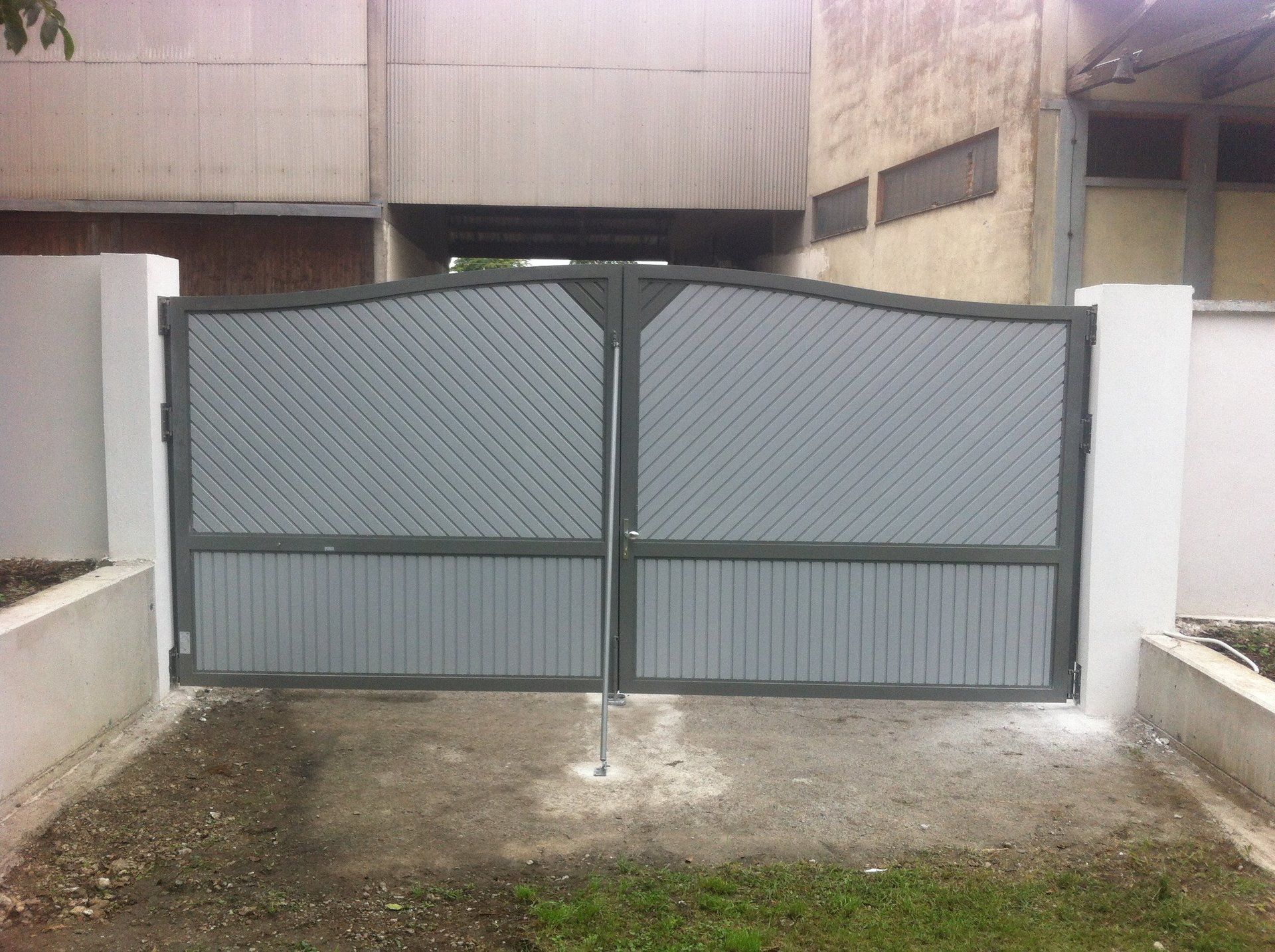 Vor einem Gebäude ist ein graues Tor geöffnet