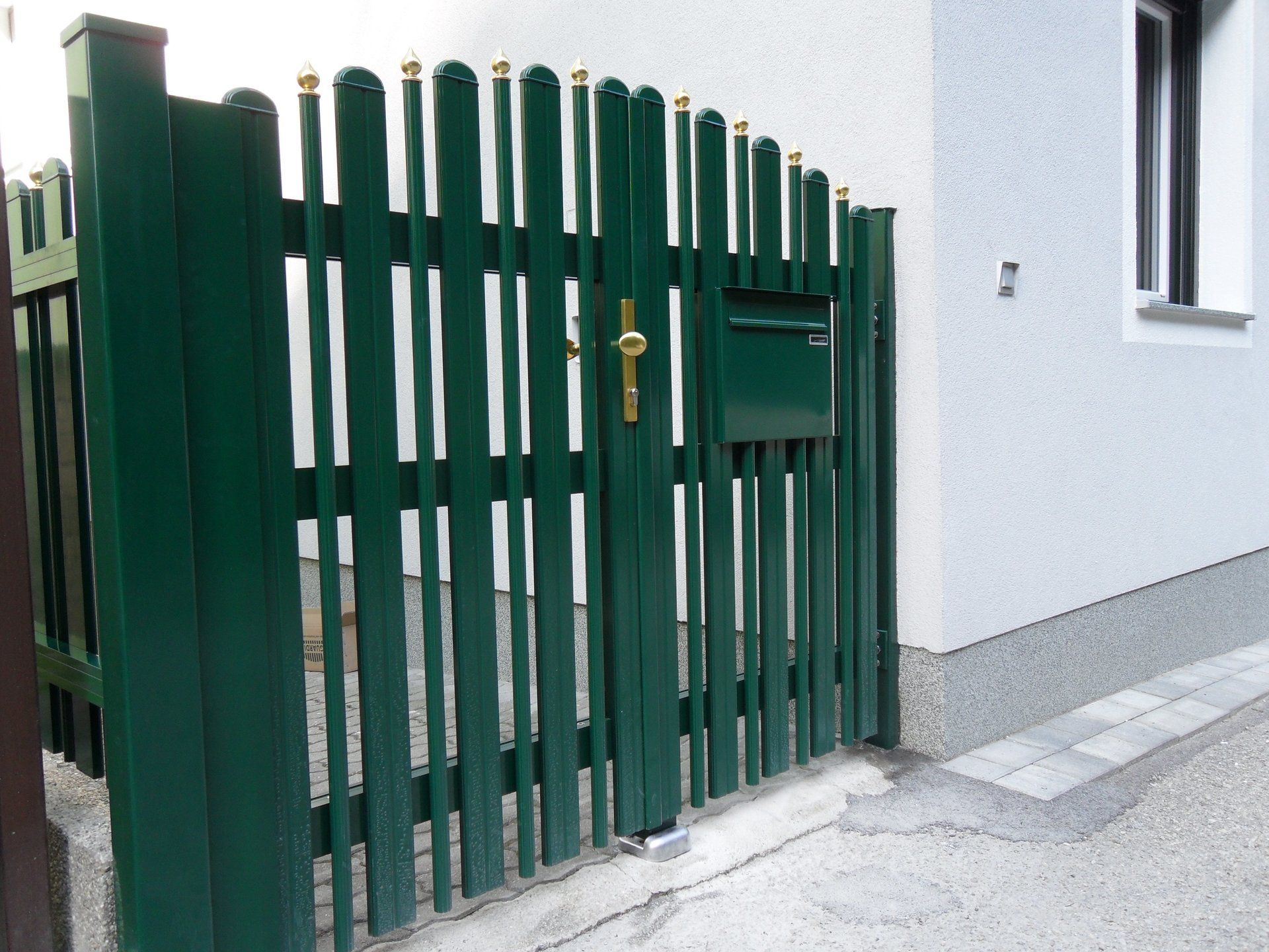 Ein grüner Zaun mit einem Briefkasten darunter