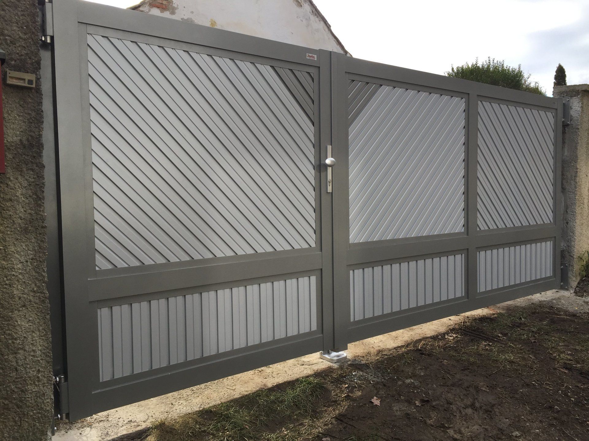 Auf einem Feld aus Erde steht ein graues Tor mit einem diagonalen Muster.