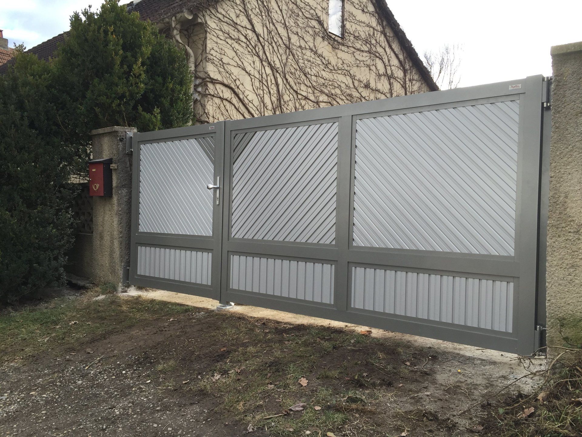 Vor einem Haus steht ein grau-weißes Tor.