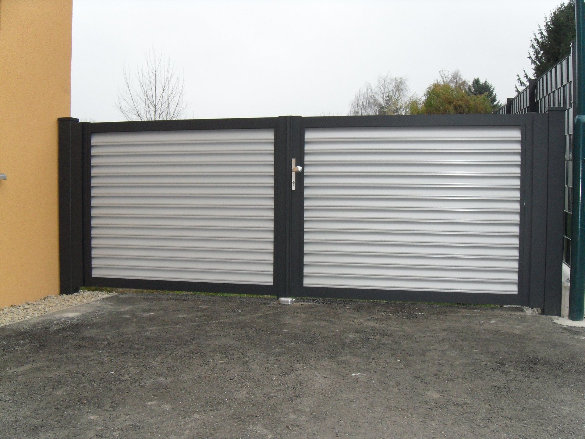 Ein grau-weißes Tor steht vor einem Gebäude