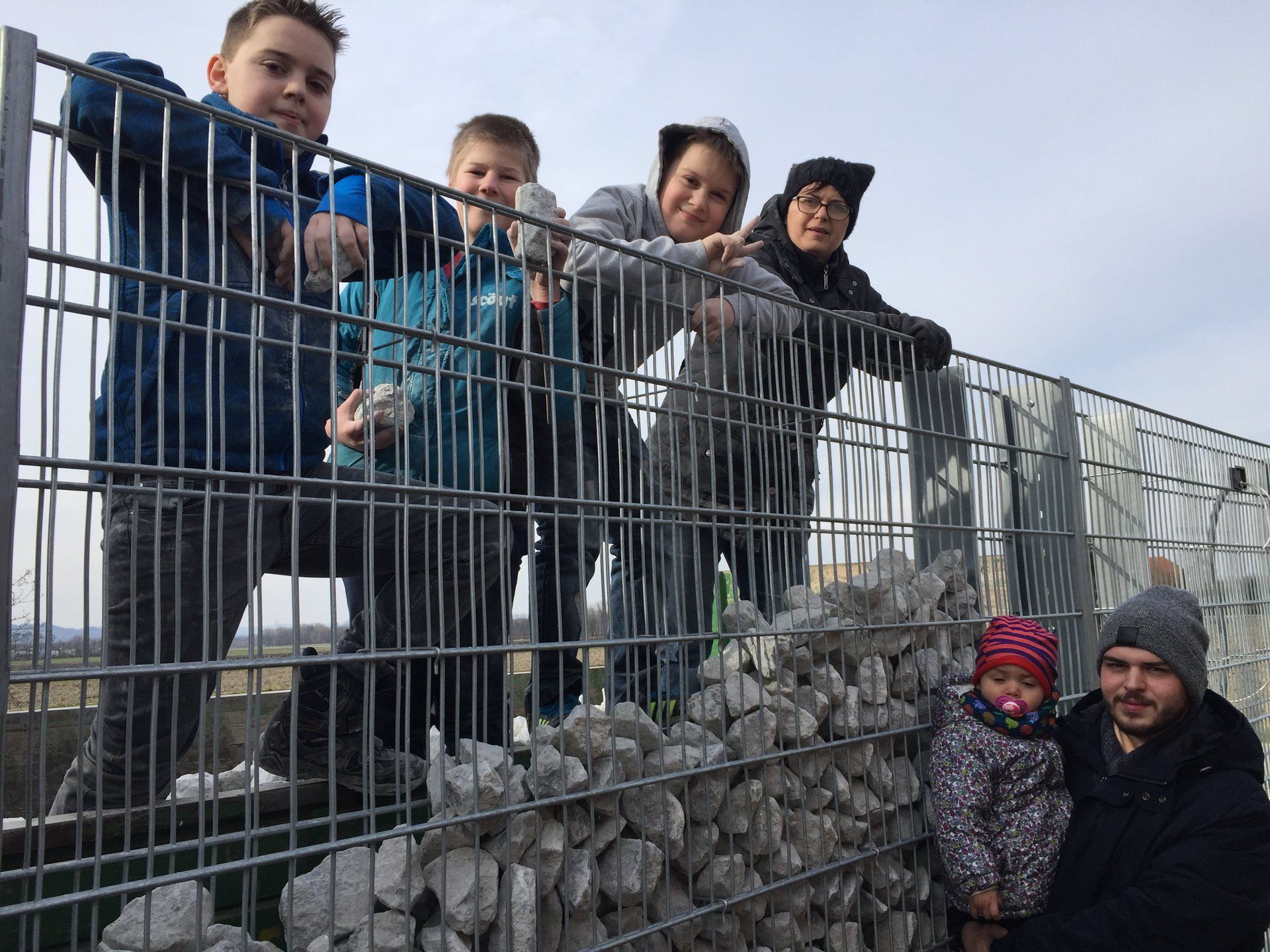 Eine Gruppe von Leuten steht hinter einem Zaun und schaut darüber hinweg.