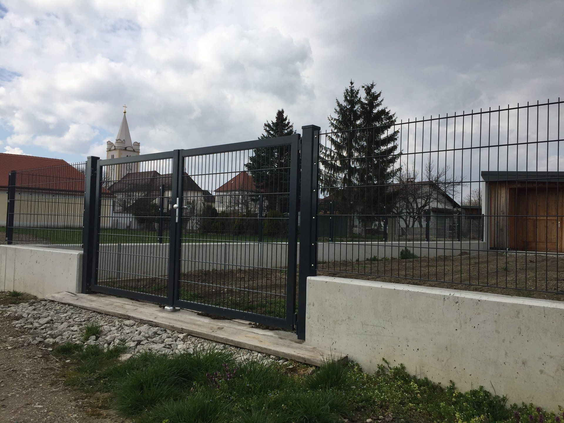 Ein Zaun mit einem Tor und einer Kirche im Hintergrund