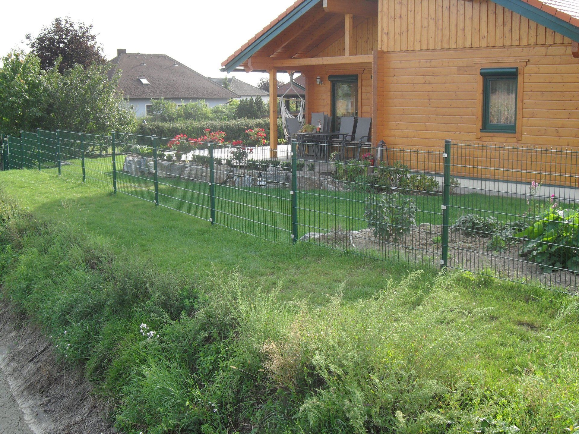 Ein Holzhaus mit einem grünen Zaun davor