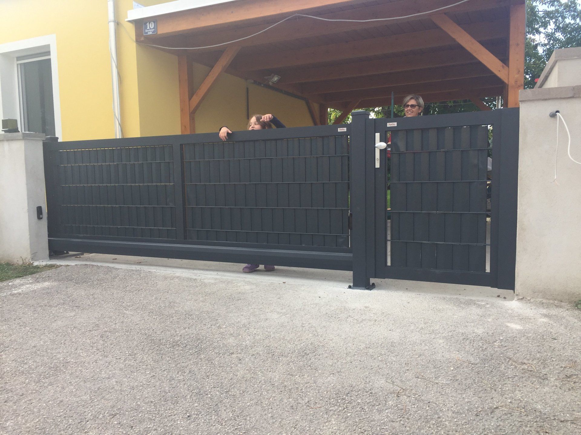 Hinter einem schwarzen Tor stehen ein paar Leute.