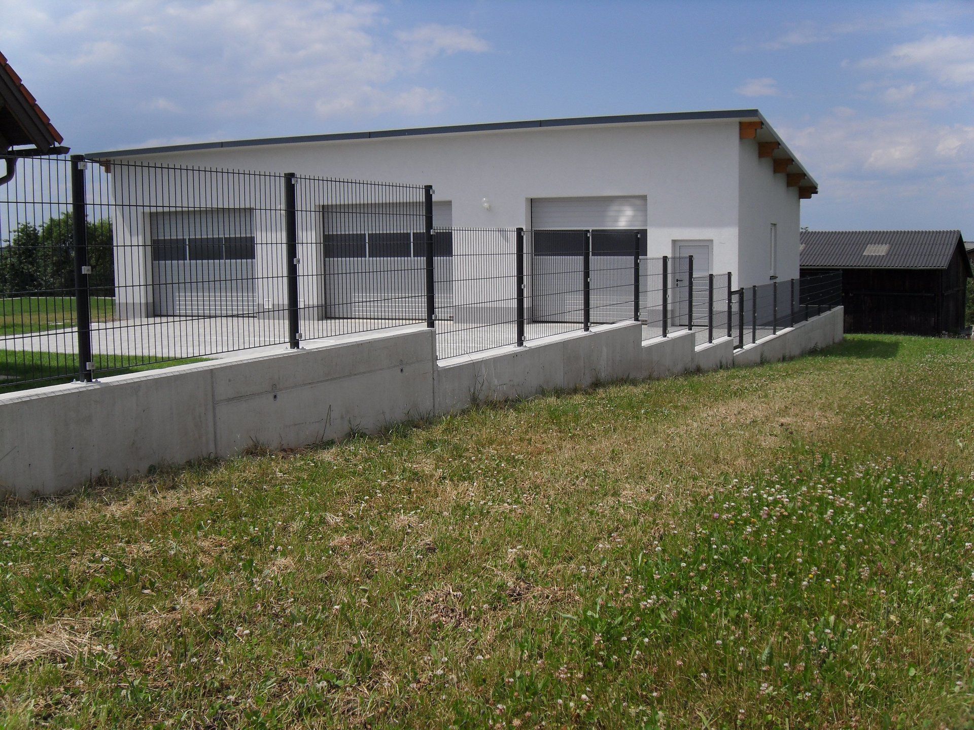 Ein weißes Gebäude mit einem schwarzen Zaun darum