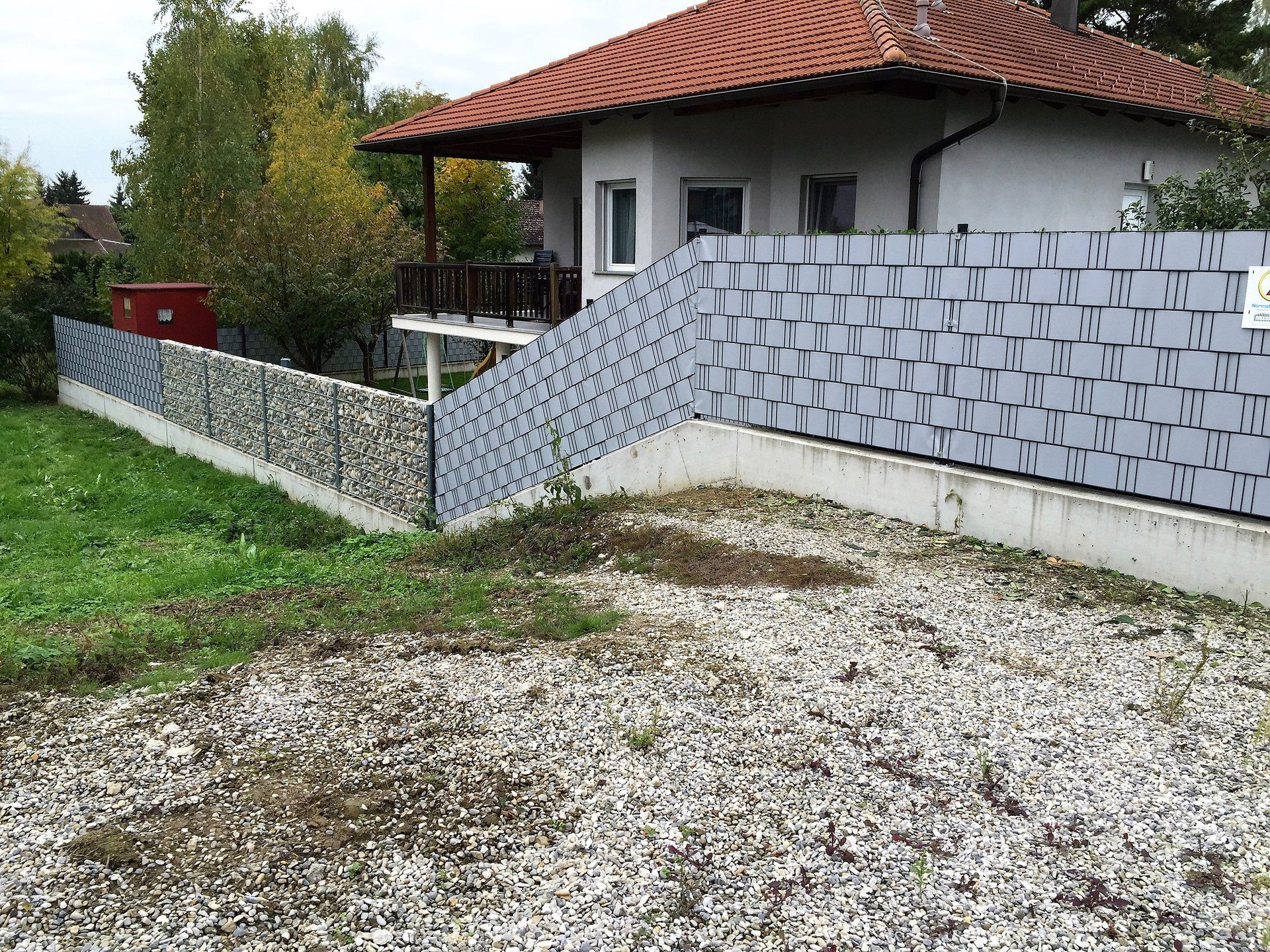 Ein Haus mit einer Kiesauffahrt und einem Zaun davor