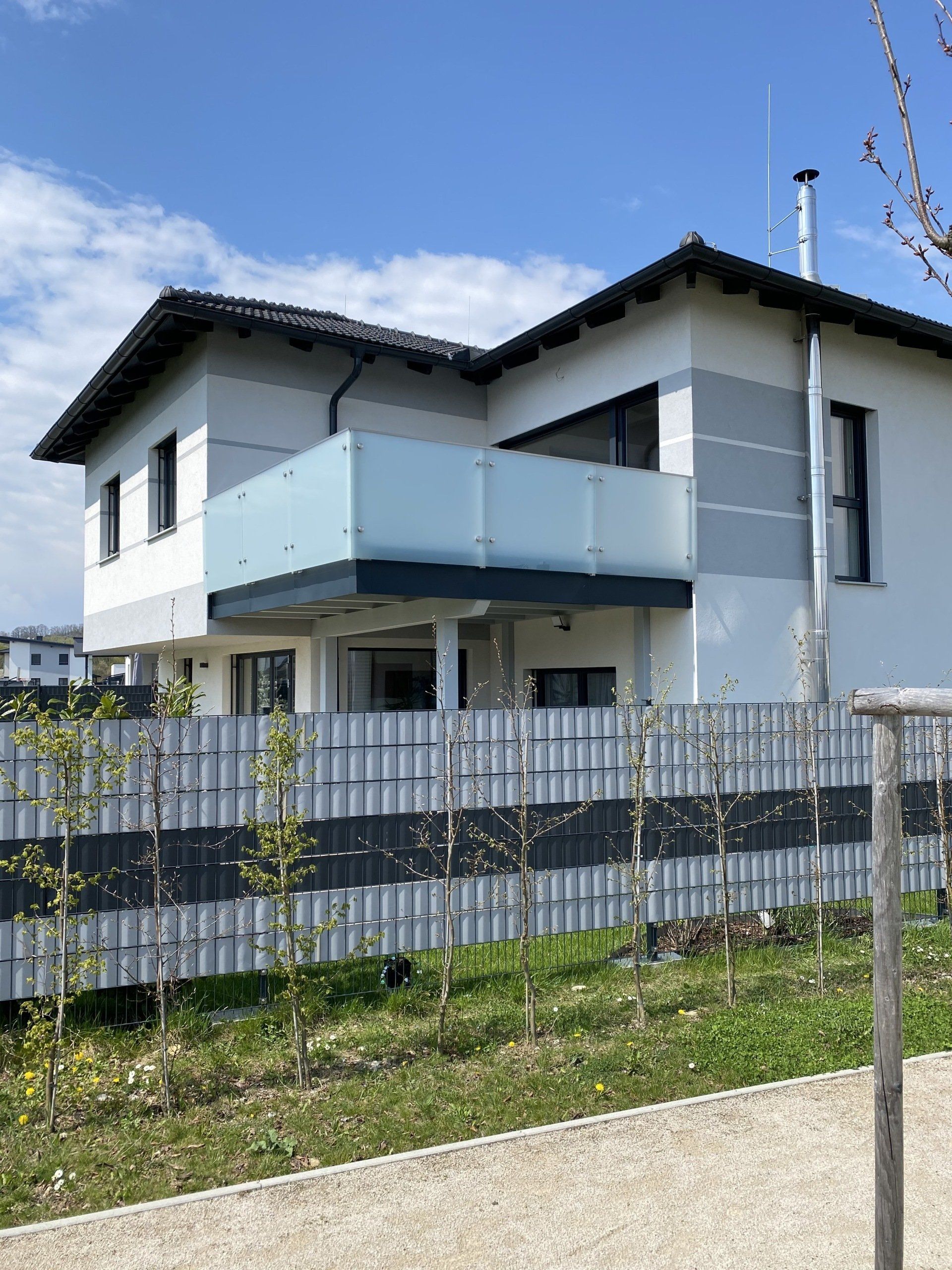 Ein großes weißes Haus mit einem Balkon und einem Zaun darum herum.