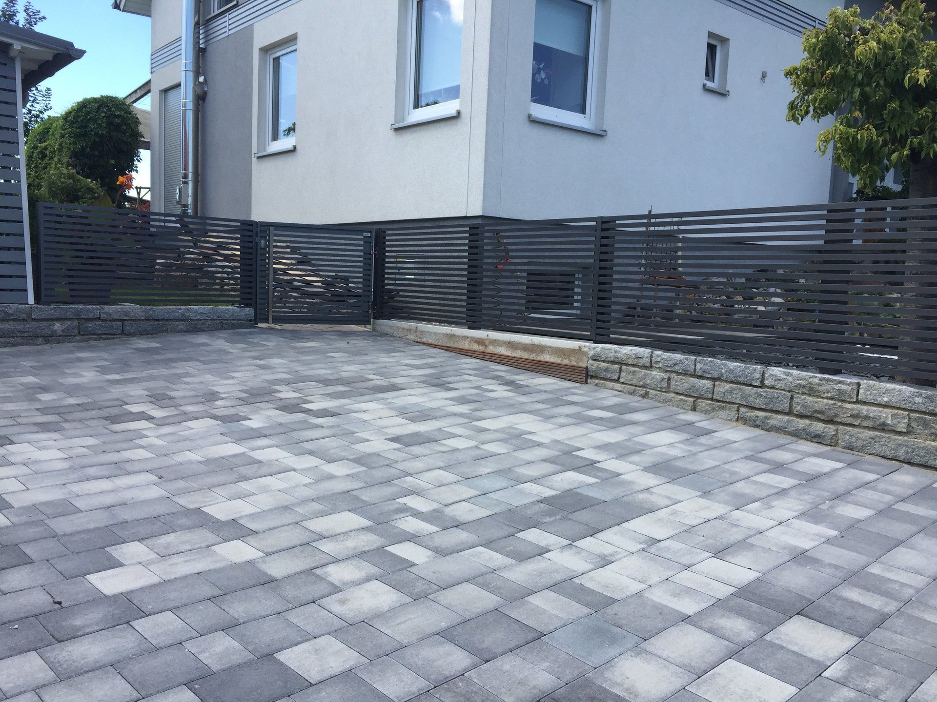 Eine gemauerte Auffahrt mit einem Zaun vor einem Haus