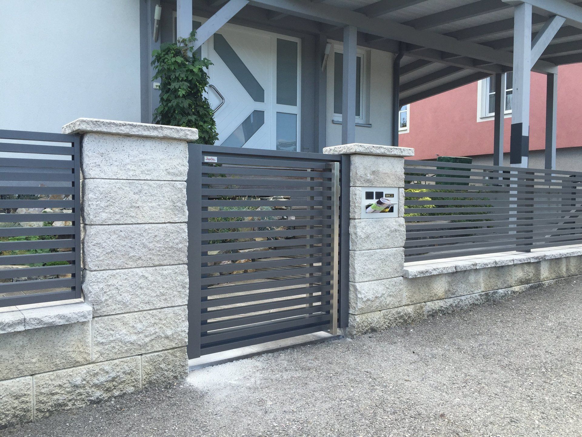 Ein Zaun mit einem Tor vor einem Haus