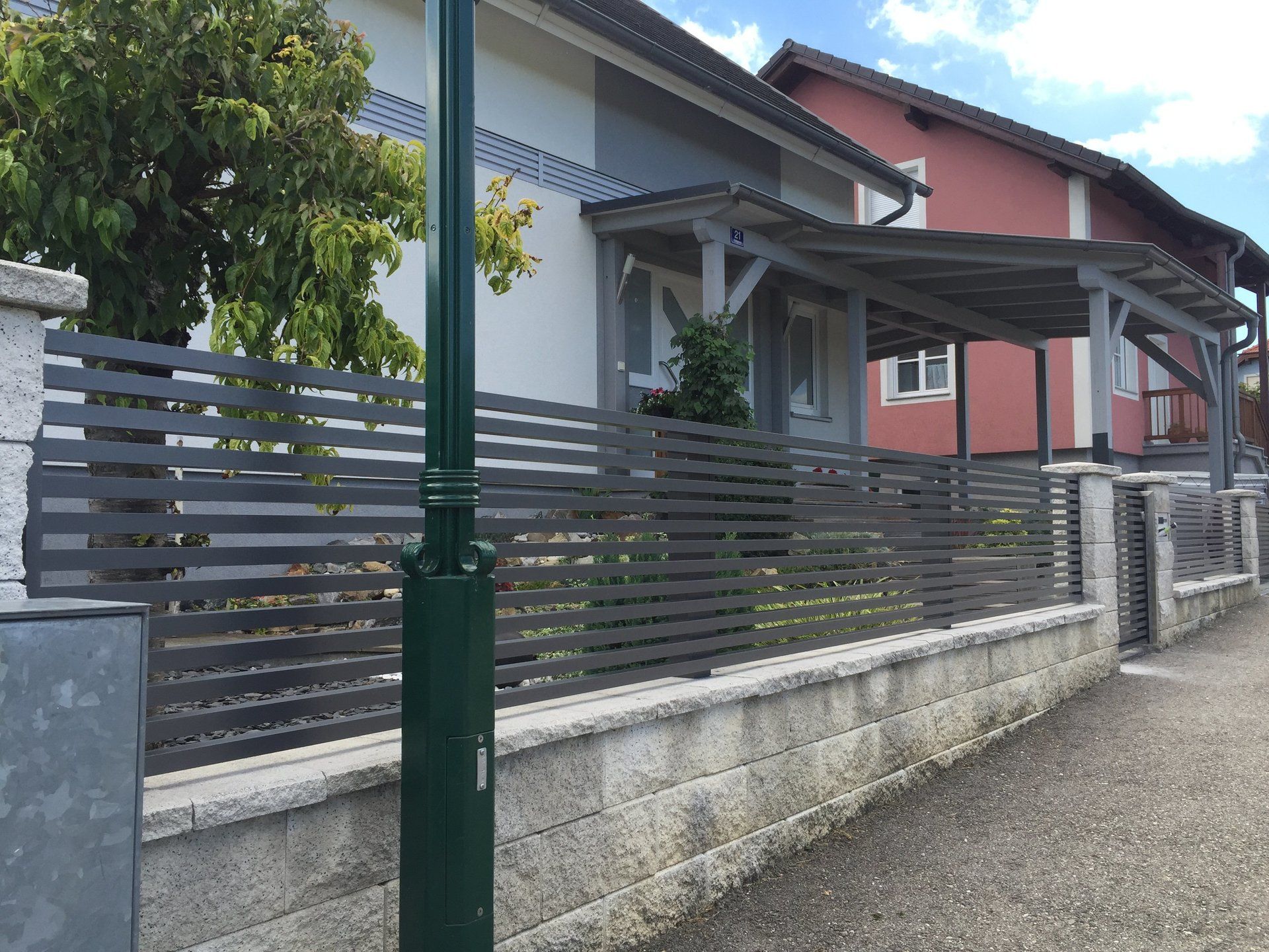 Ein Zaun mit einem grünen Pfosten vor einem Haus