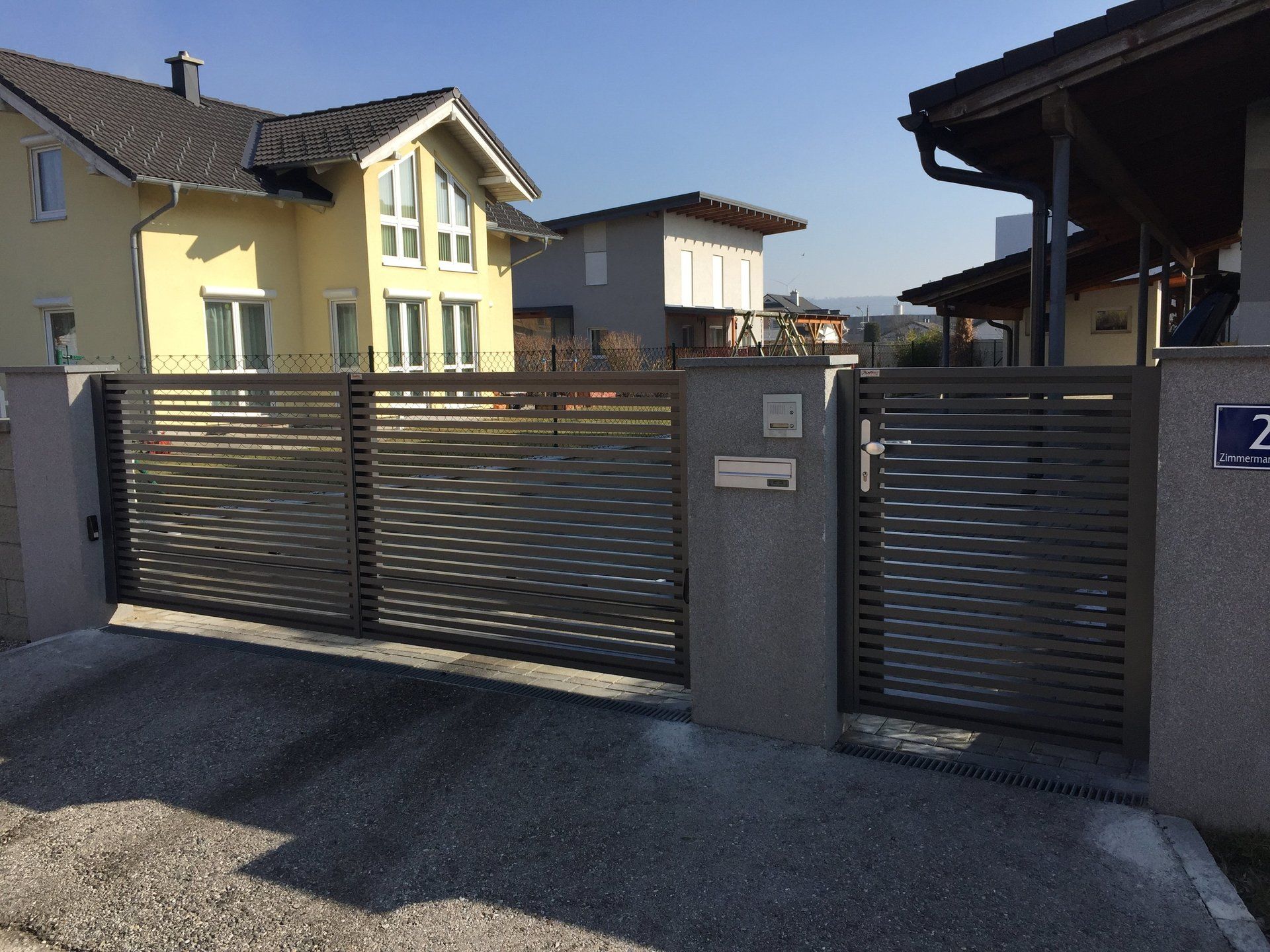 Hinter einem Zaun steht ein gelbes Haus mit der Nummer 2 darauf