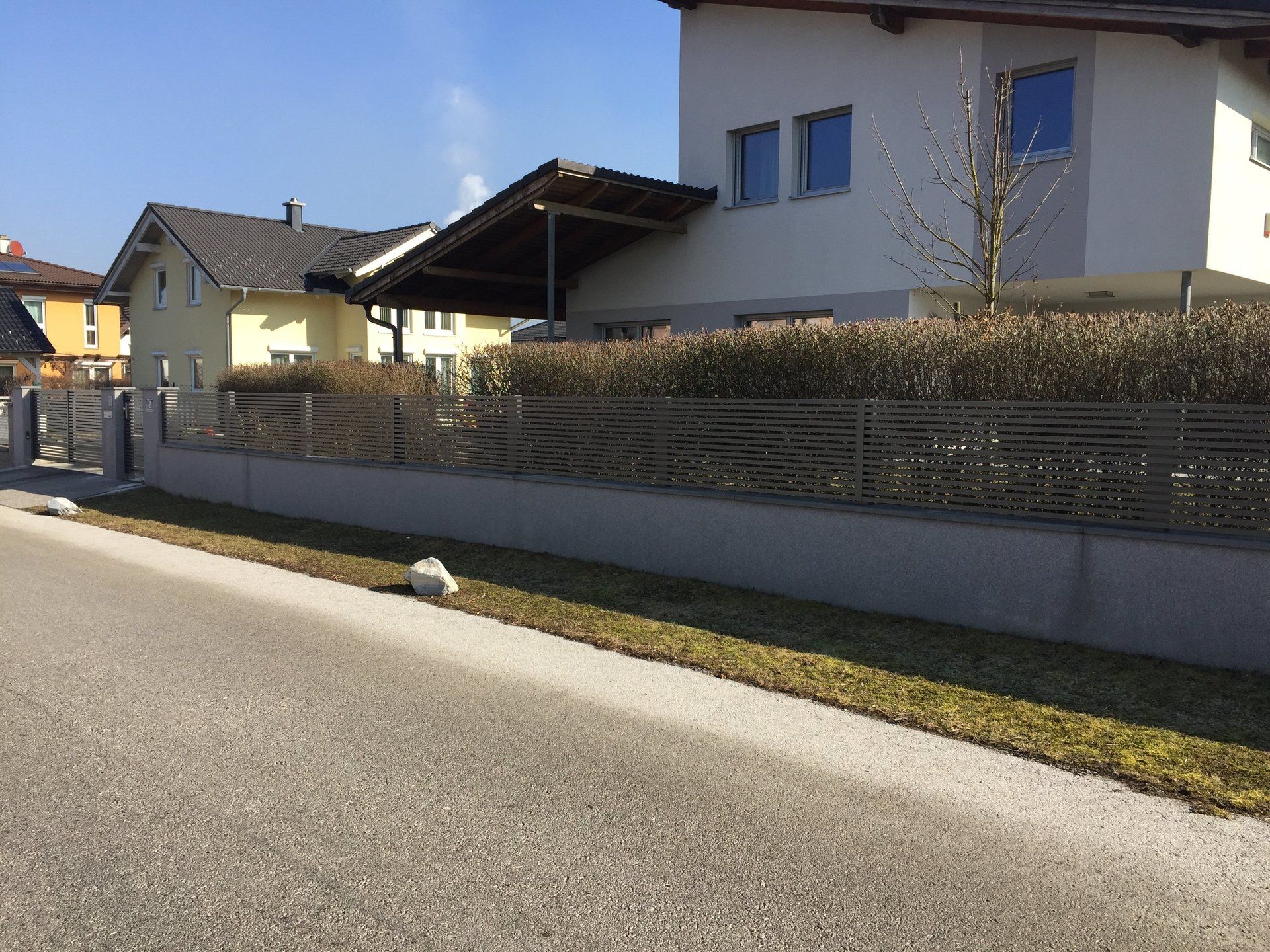 Ein Haus mit einem Zaun steht neben einer Straße