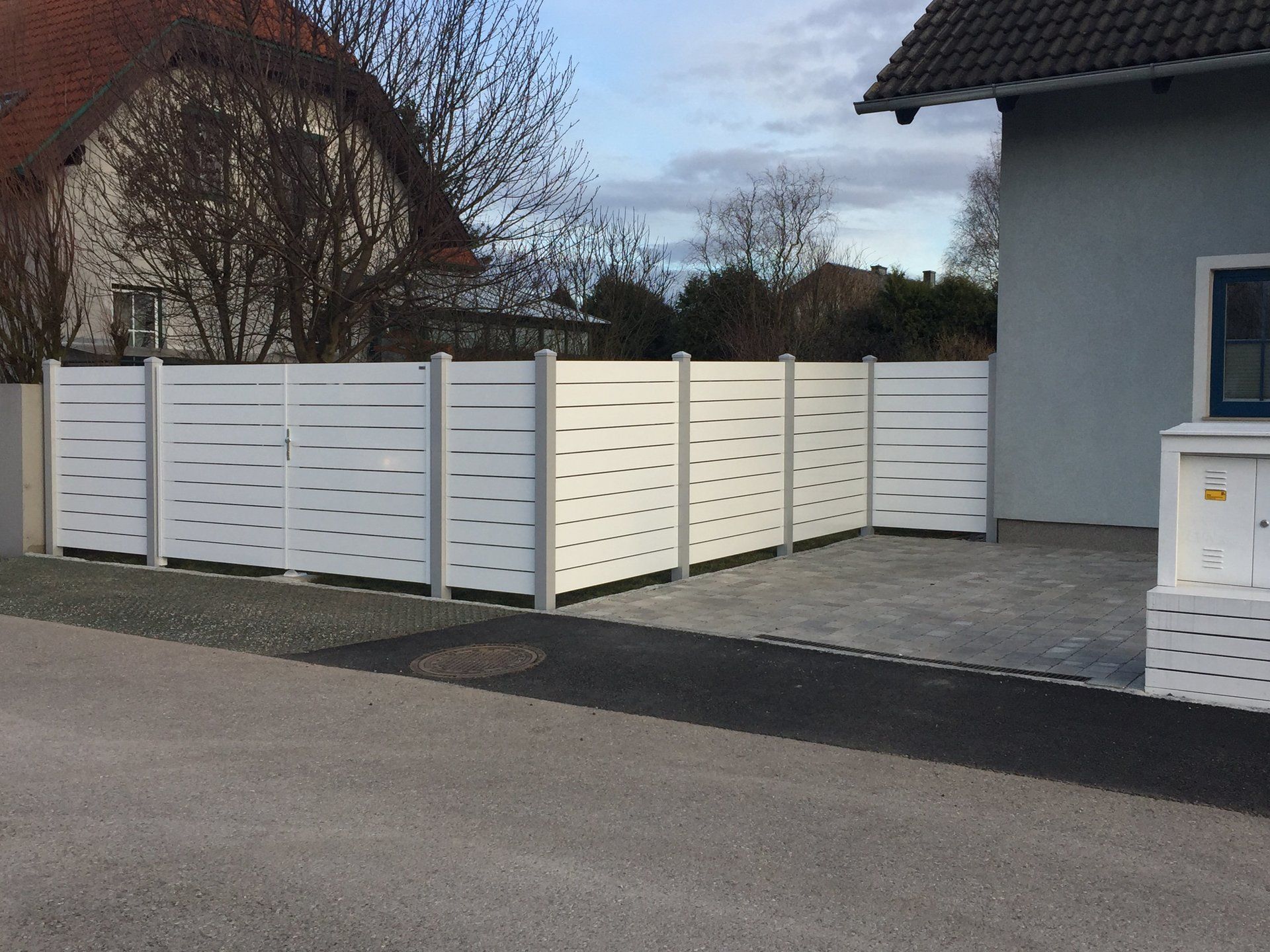 Ein weißer Zaun steht vor einem Haus