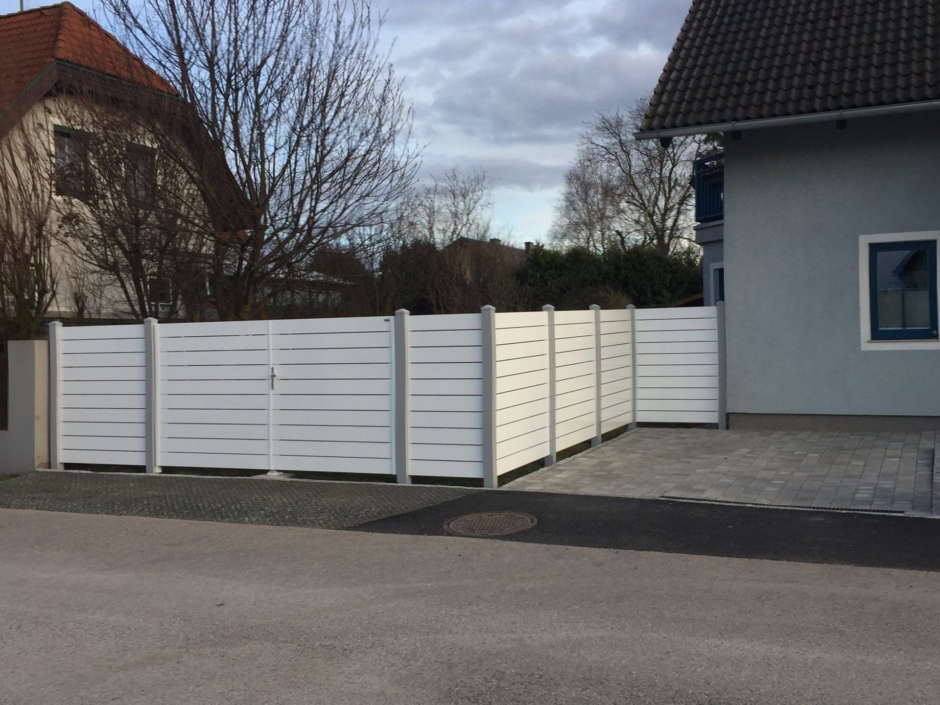 Ein weißer Zaun steht vor einem Haus