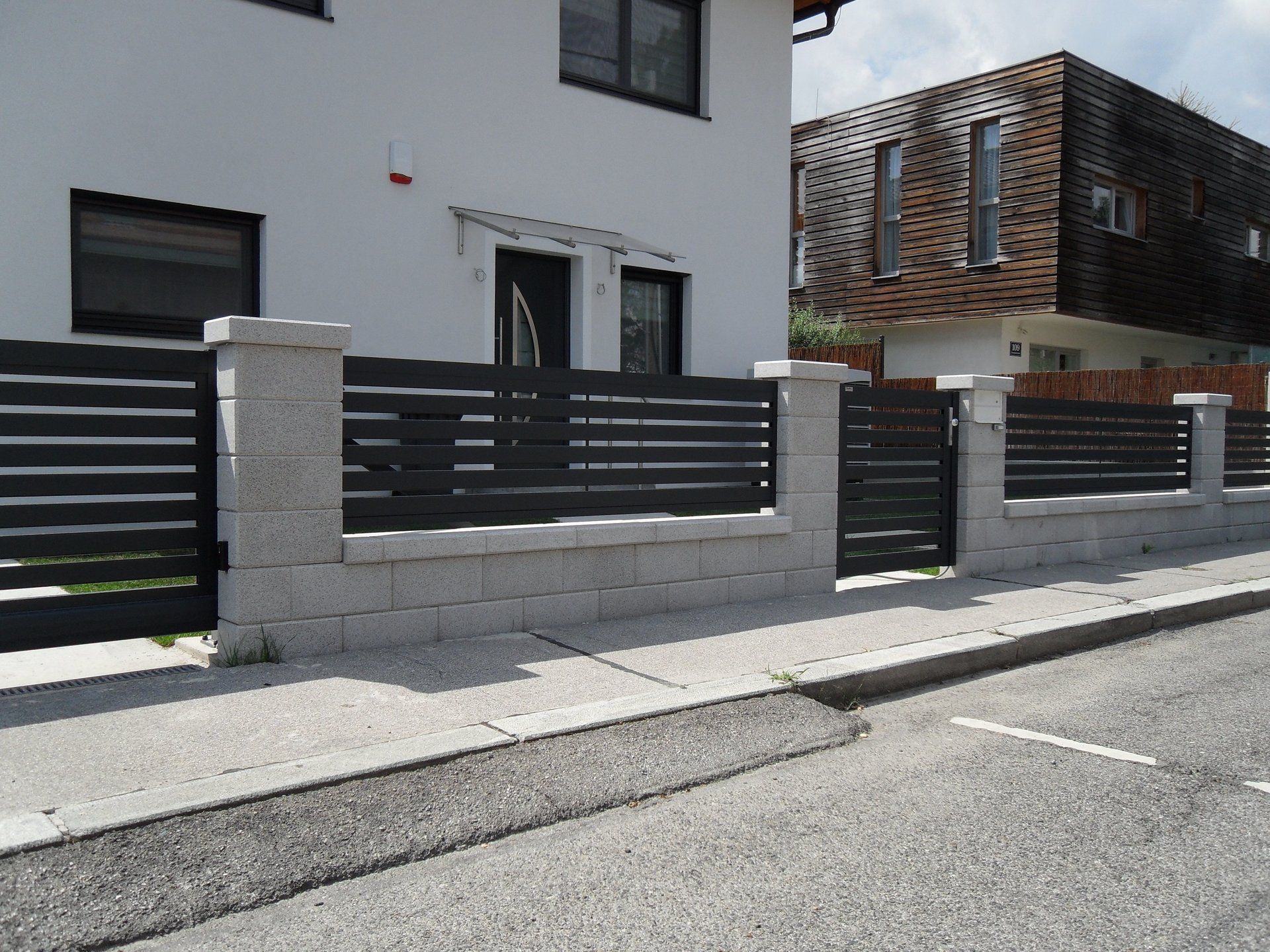 Ein weißes Haus mit einem schwarzen Zaun und einem Tor