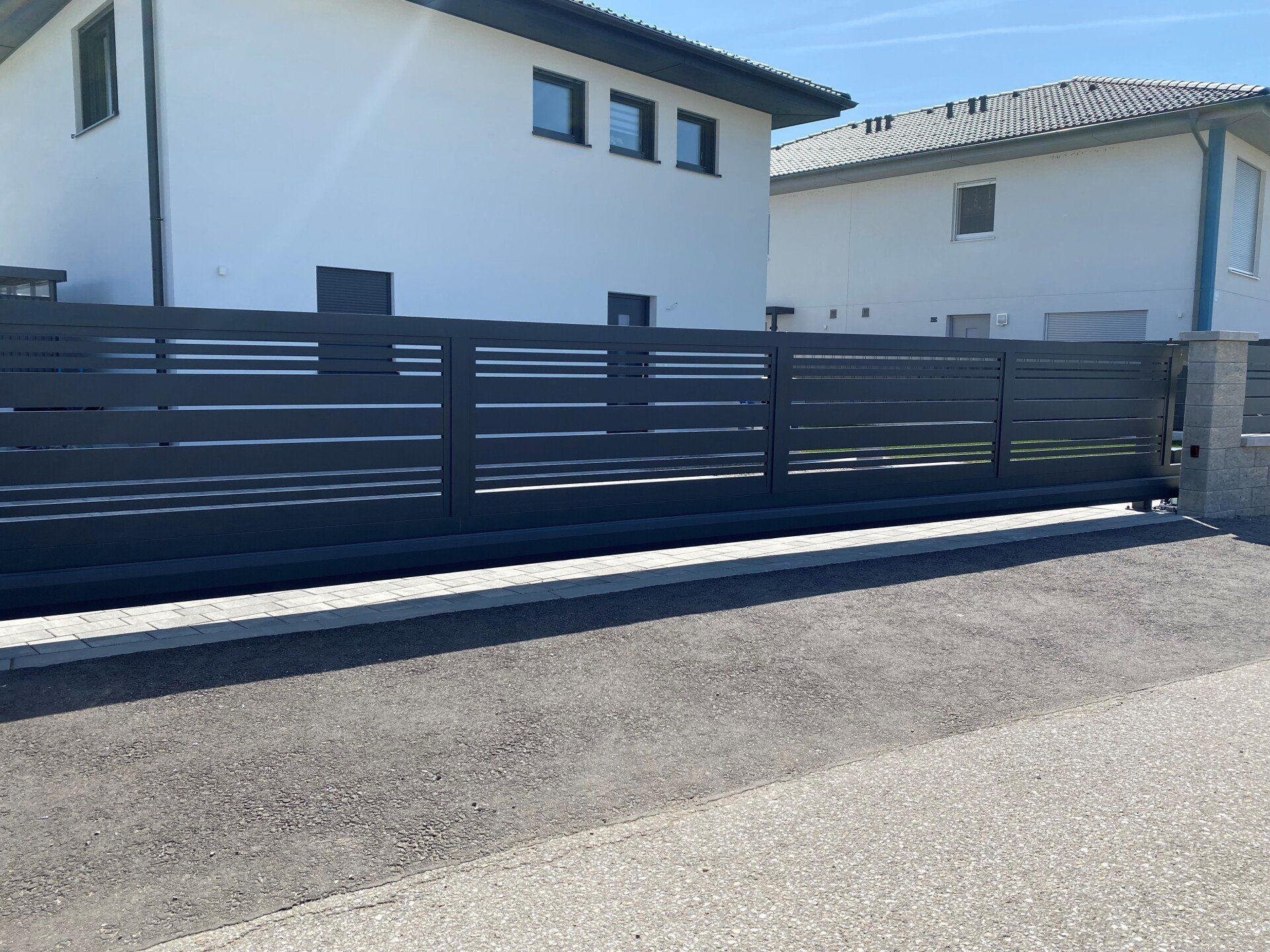 Ein weißes Haus mit einem schwarzen Zaun davor