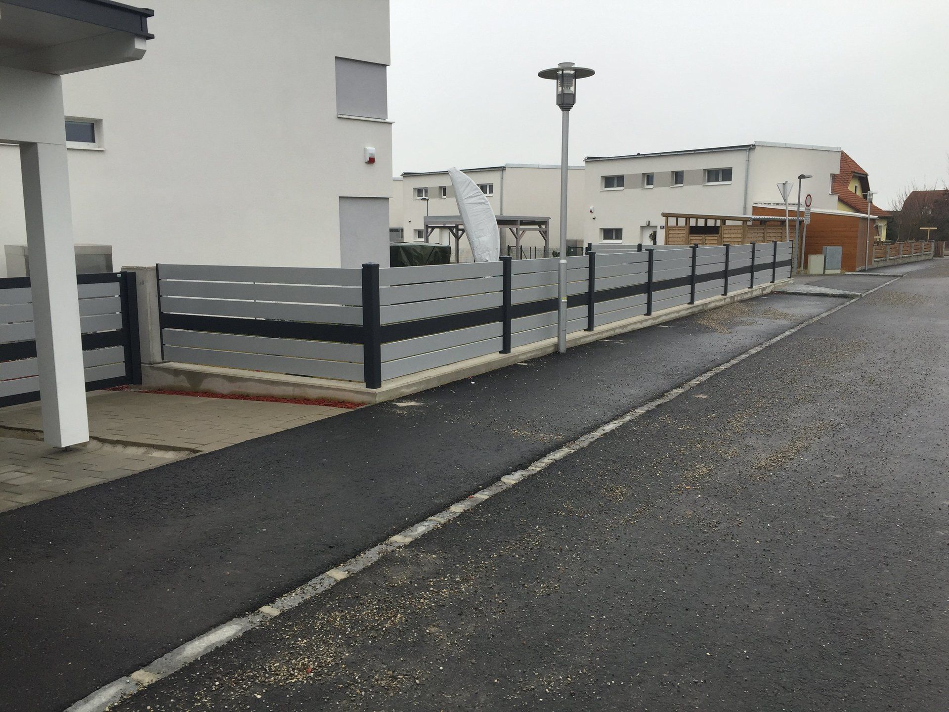 Ein Zaun entlang der Seite einer Straße in einem Wohngebiet