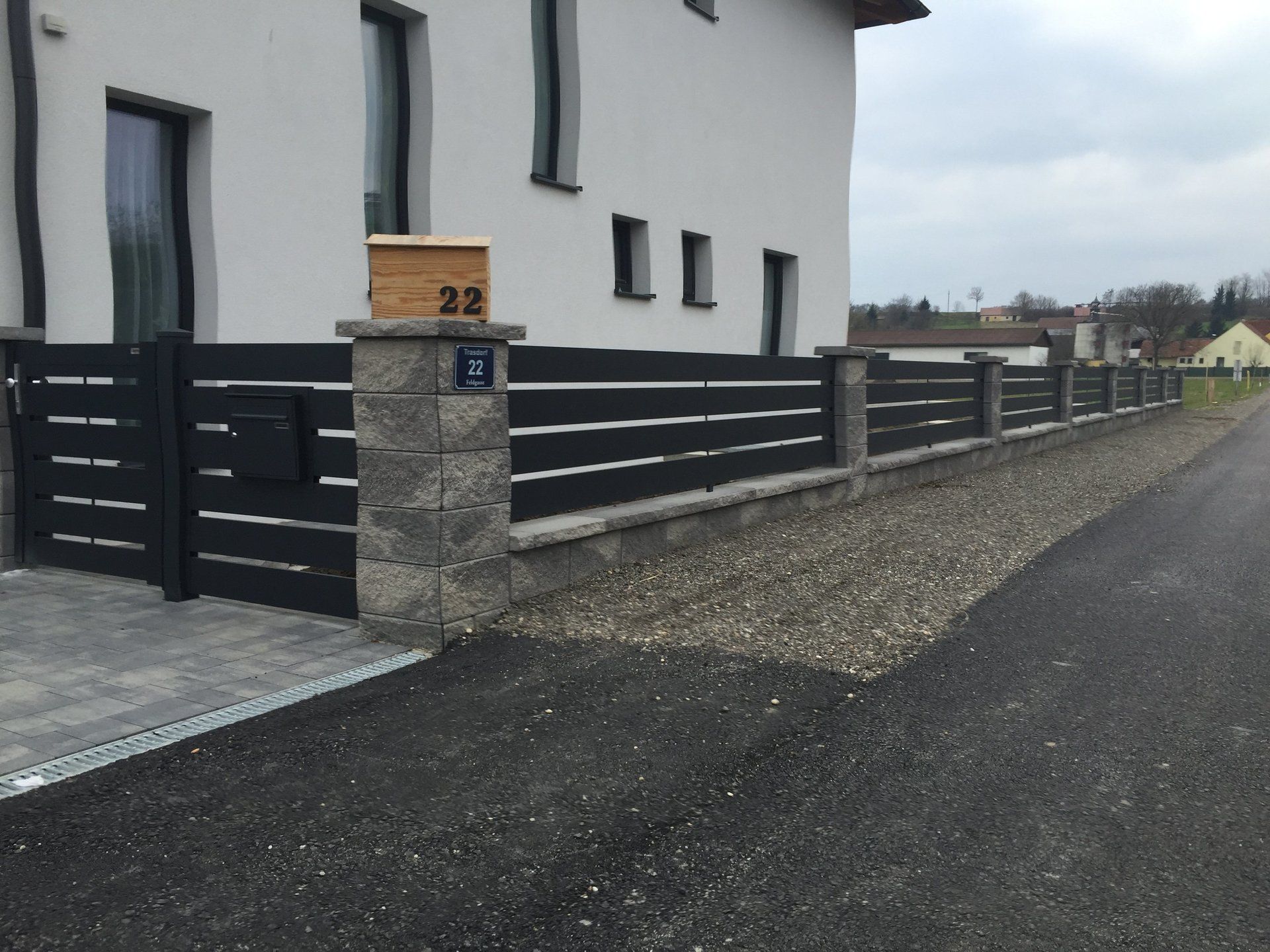 Ein weißes Haus mit einem schwarzen Zaun und einem Briefkasten mit der Nummer 22 darauf