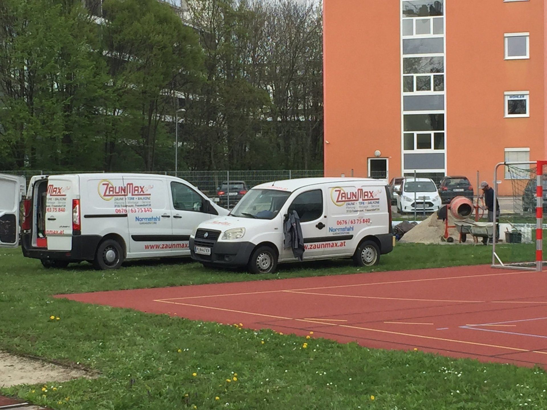 Zwei weiße Lieferwagen stehen vor einem orangefarbenen Gebäude