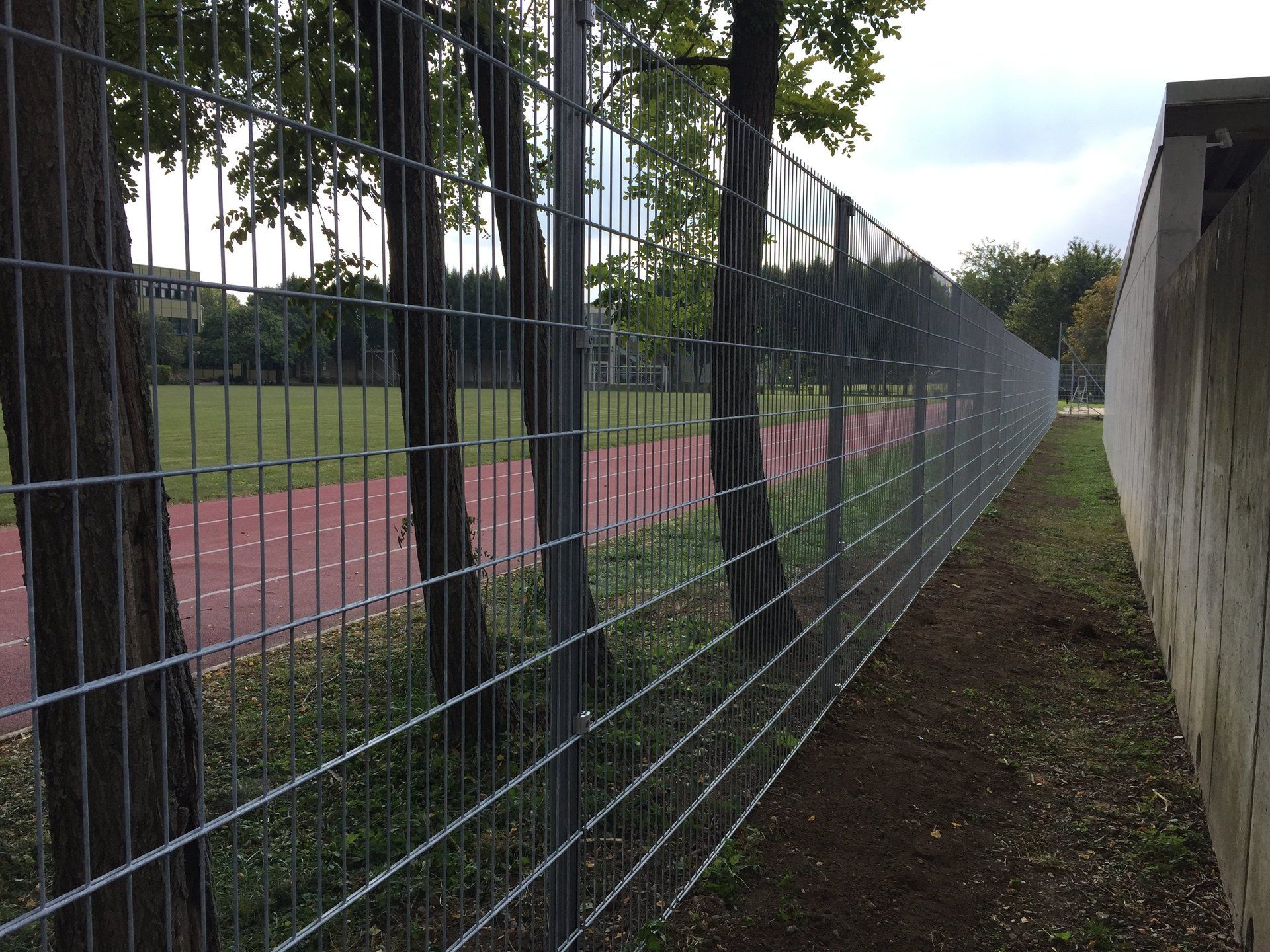 Ein Zaun umgibt ein Feld mit einem Weg im Hintergrund.