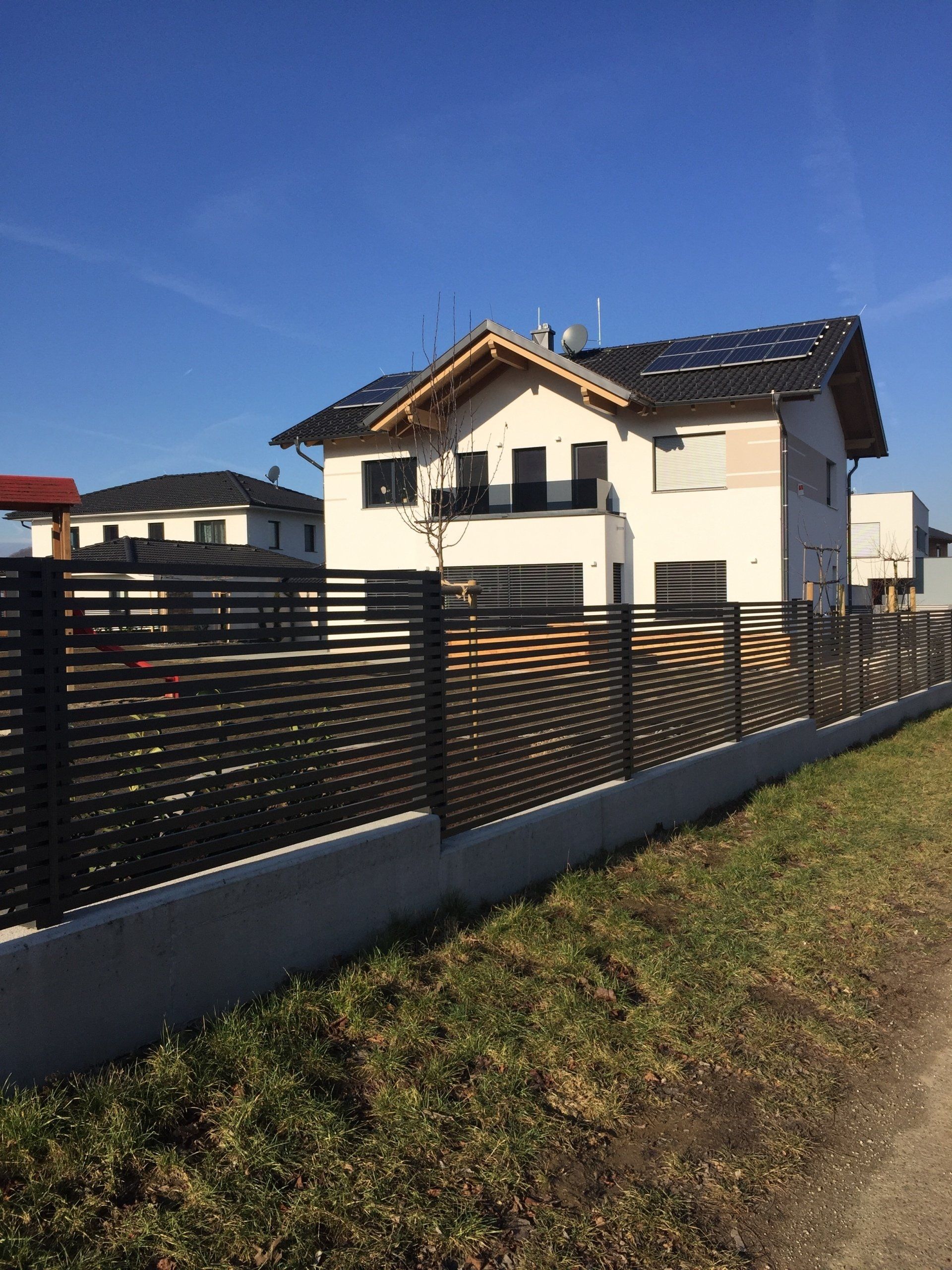 Ein großes weißes Haus mit einem schwarzen Zaun davor.