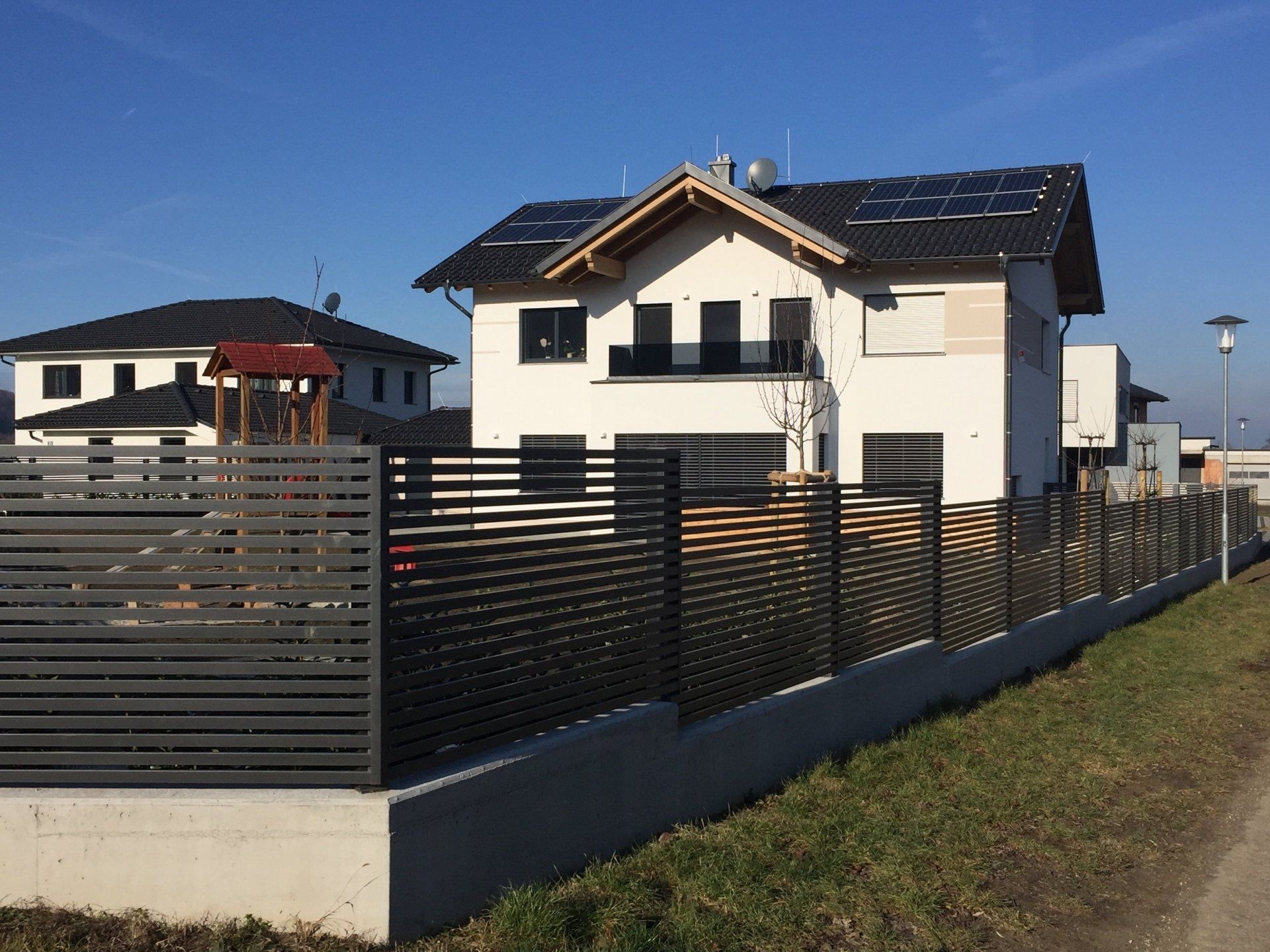 Ein weißes Haus mit einem schwarzen Zaun davor