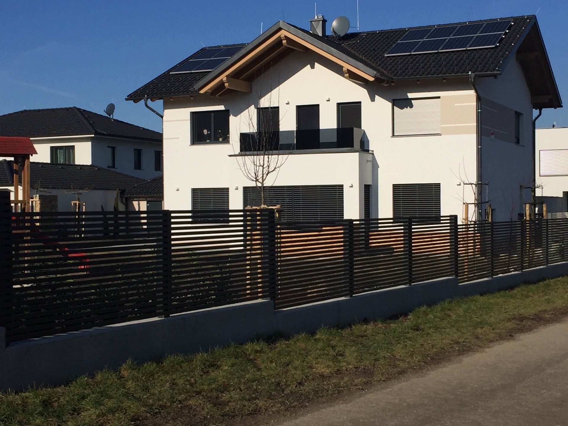 Ein großes weißes Haus mit einem schwarzen Zaun davor