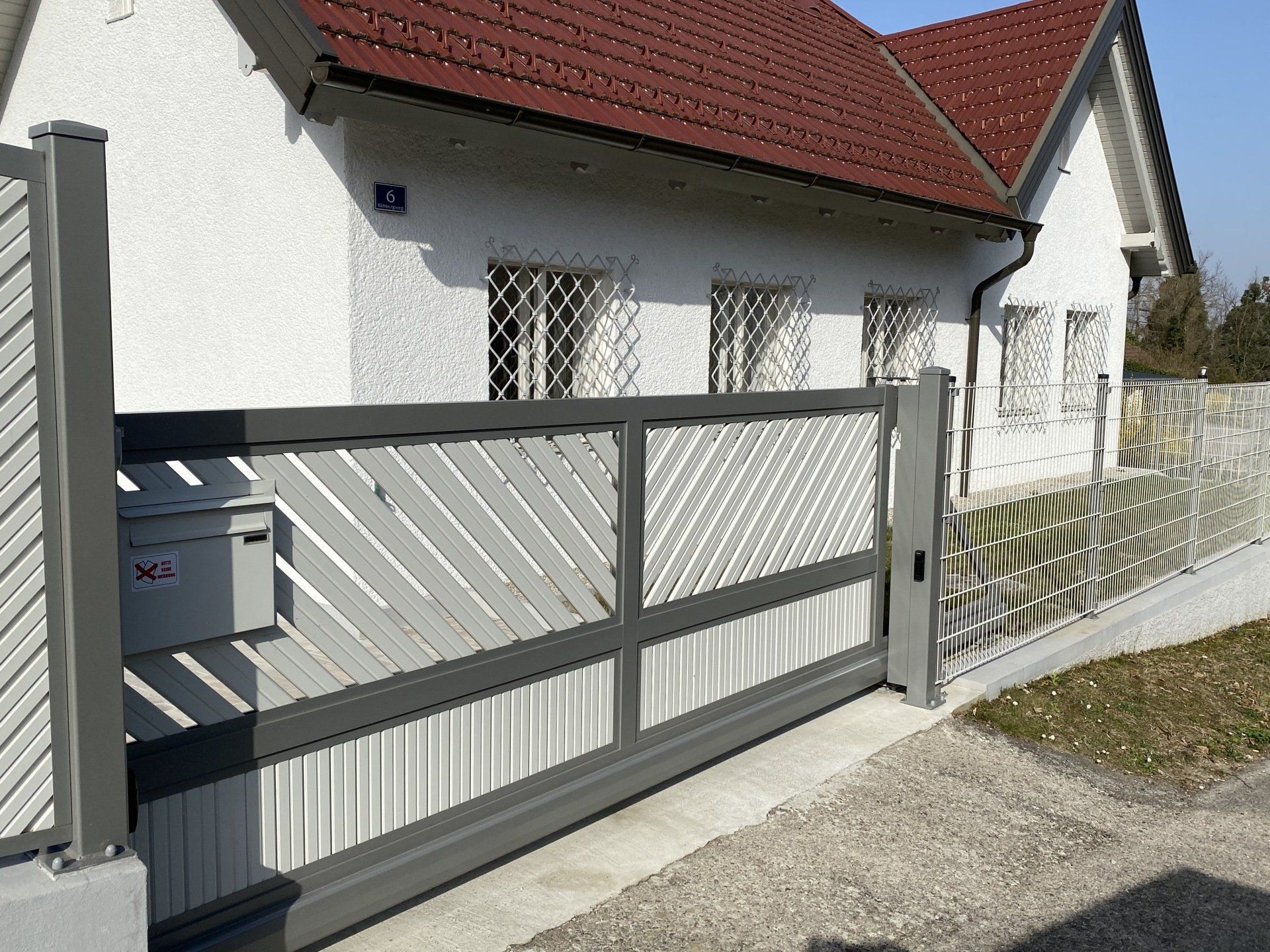 Ein weißes Haus mit einem Schiebetor davor