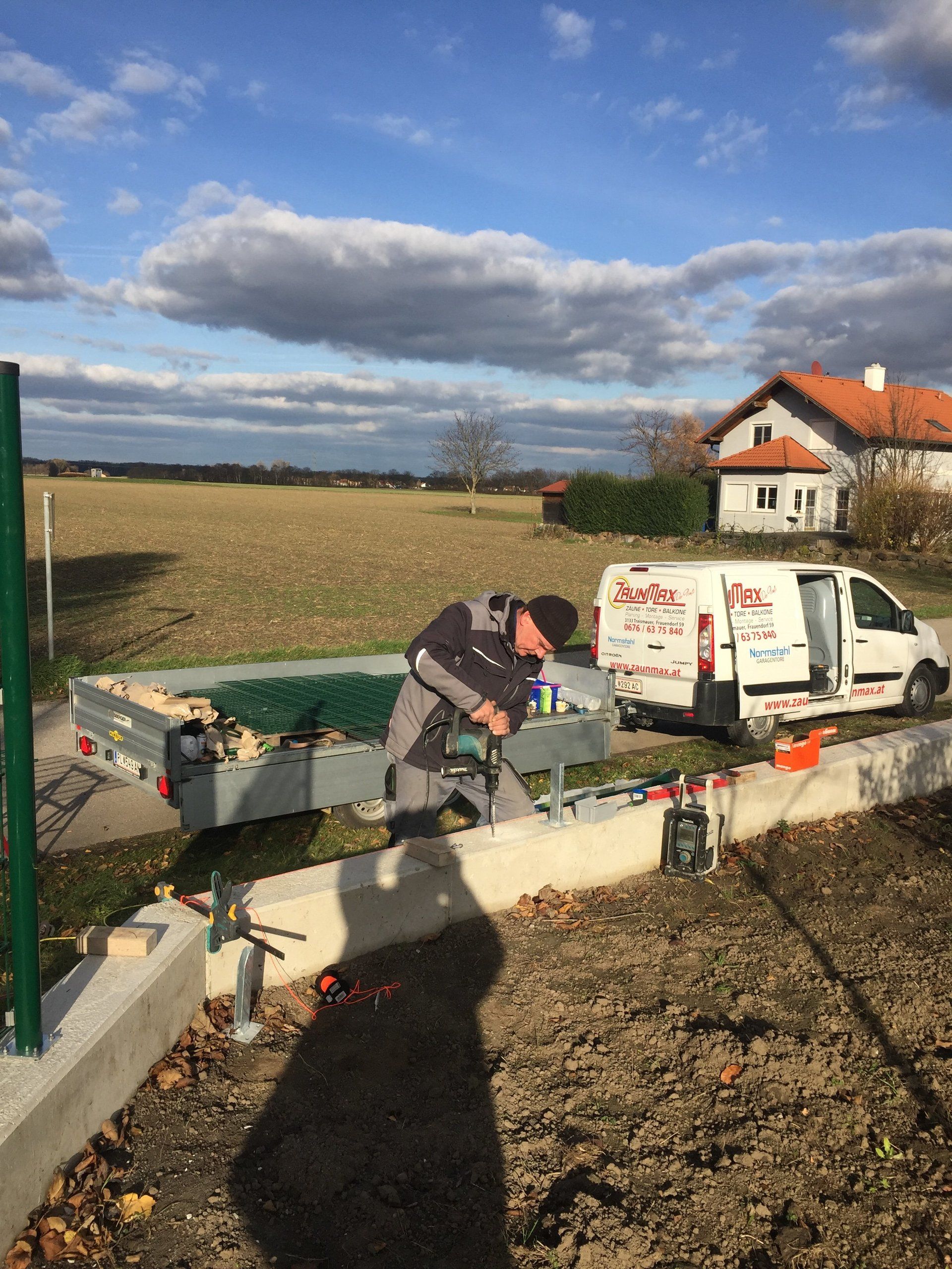 Ein Mann arbeitet an einem Zaun neben einem weißen Lieferwagen.