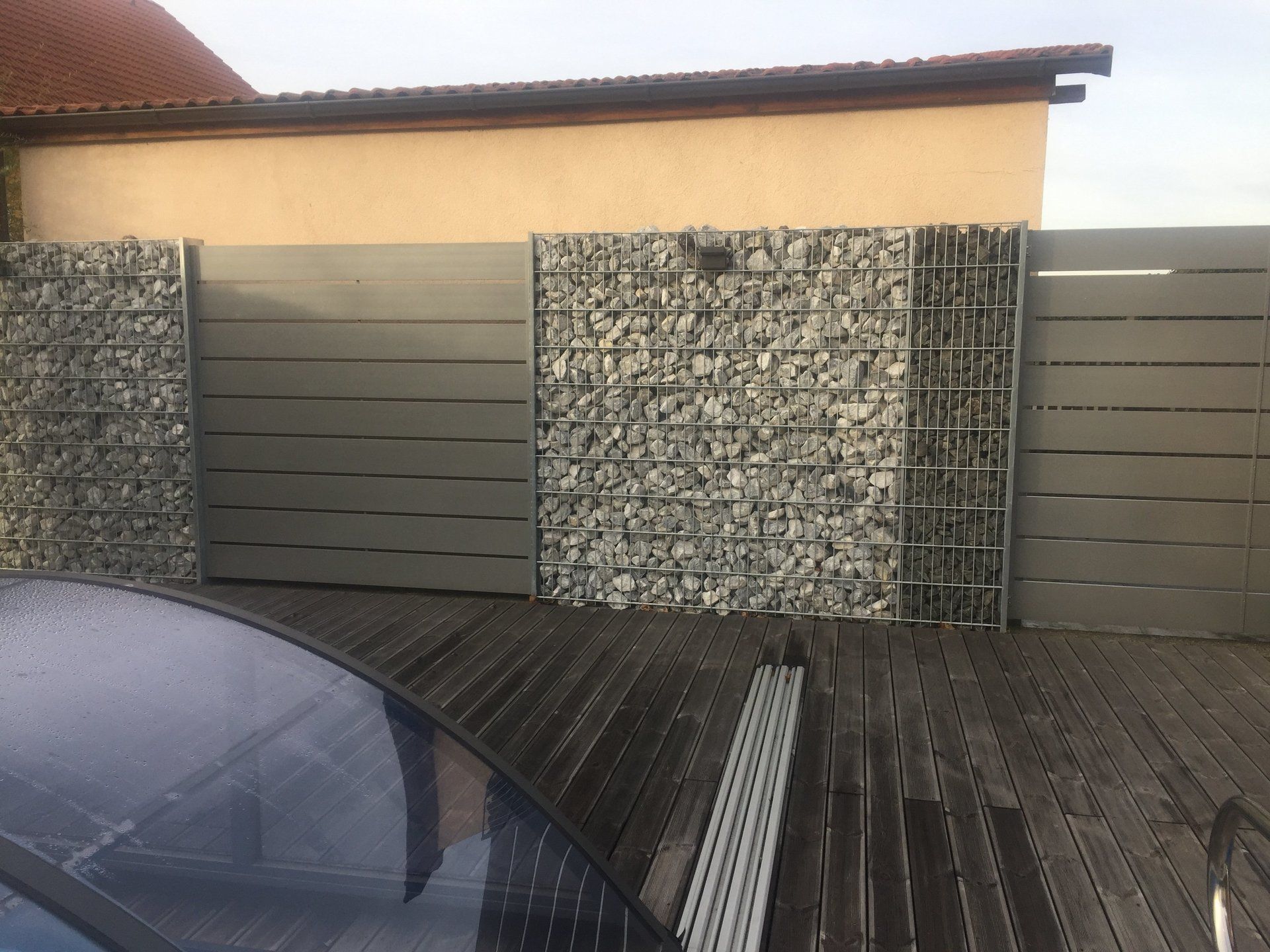 Ein Auto ist auf einem Holzdeck vor einer Steinmauer geparkt.