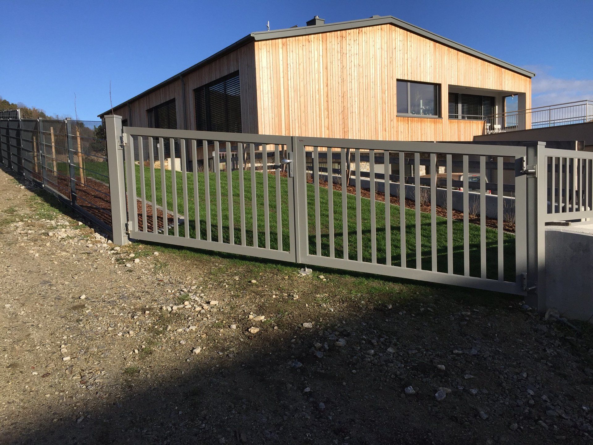 Ein Haus mit einem Zaun darum und einem Schiebetor