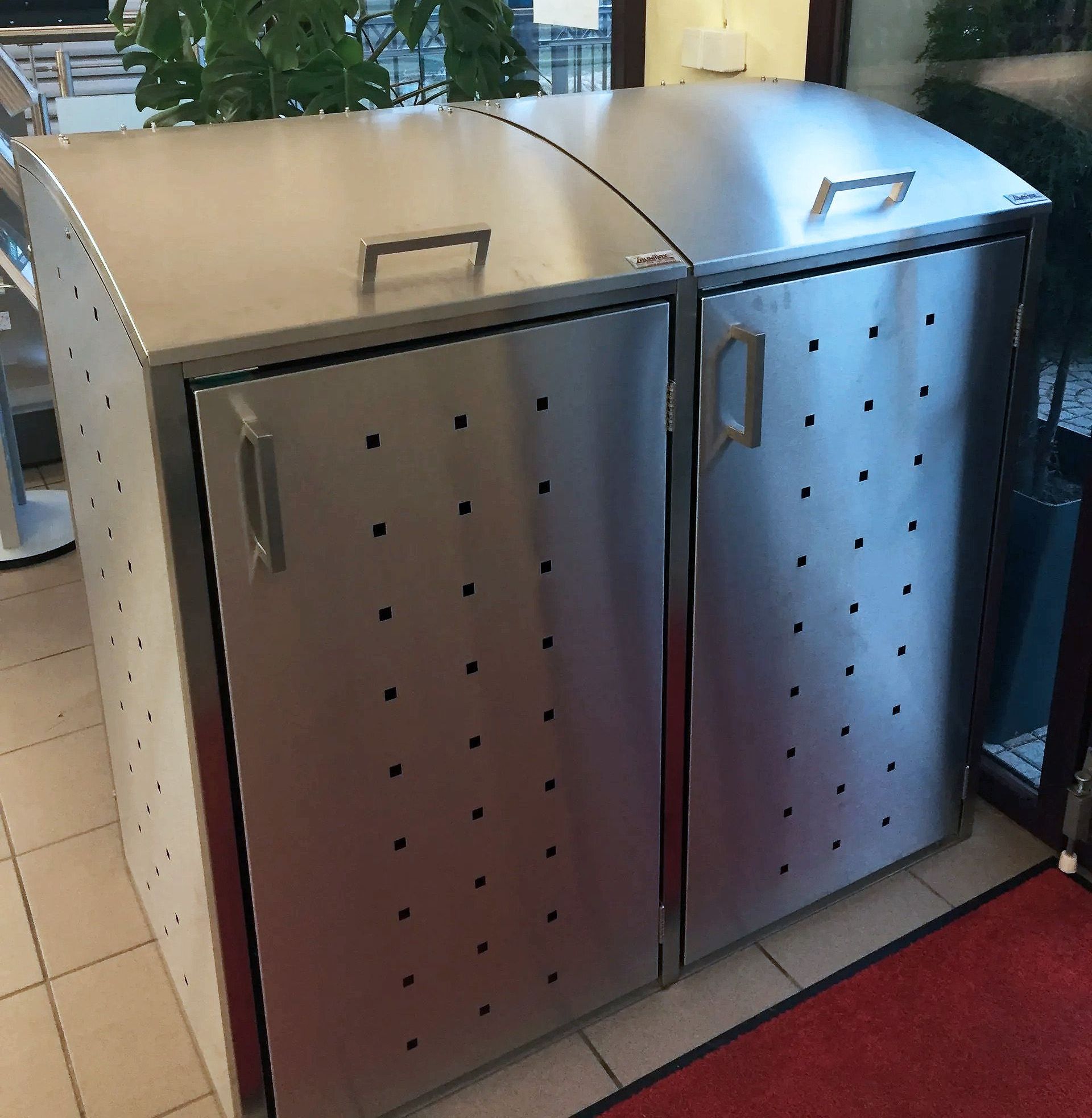 Ein Mülleimer aus Edelstahl steht auf einem gefliesten Boden