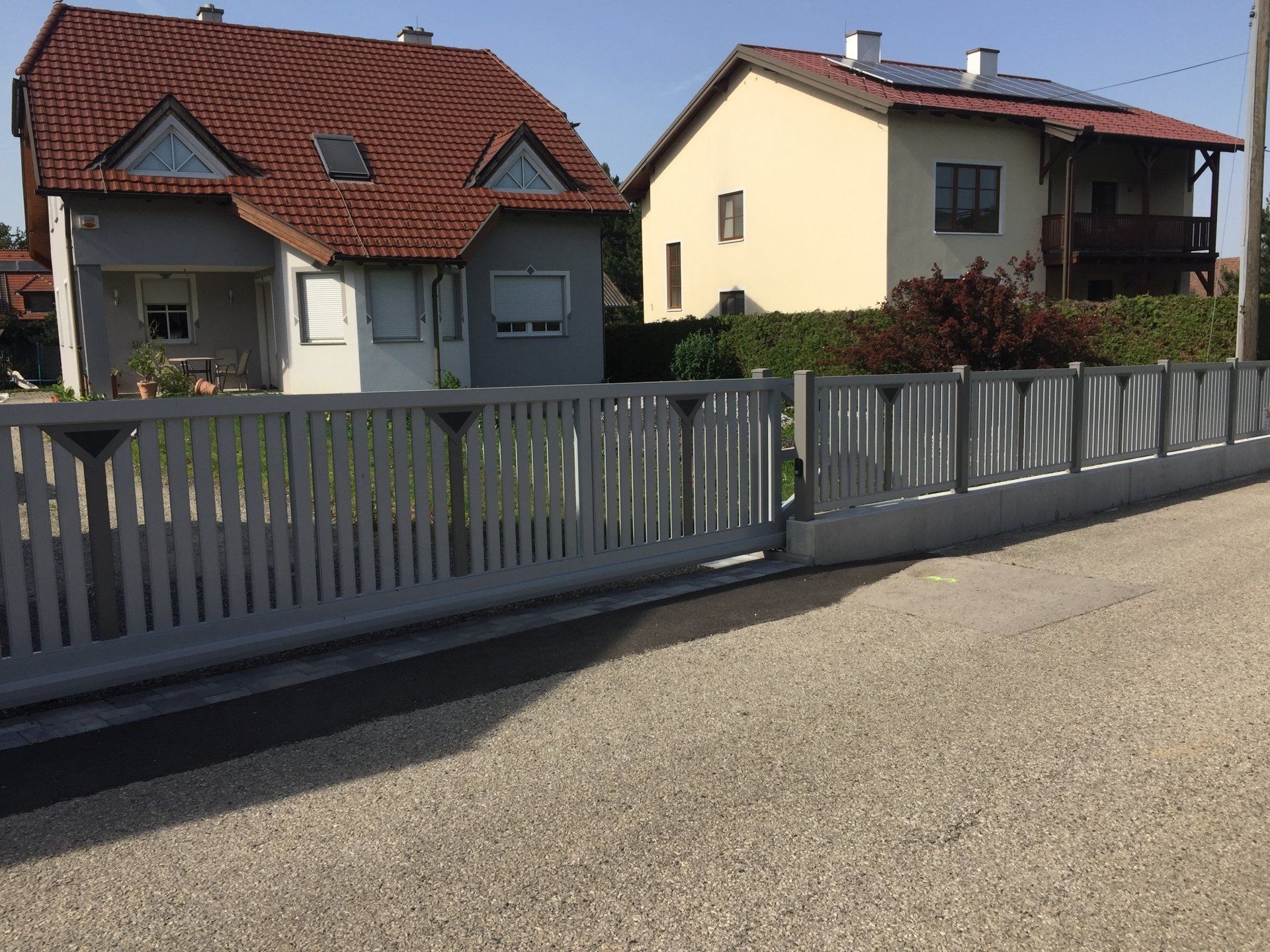 Ein Zaun mit Schiebetor vor einem Haus.