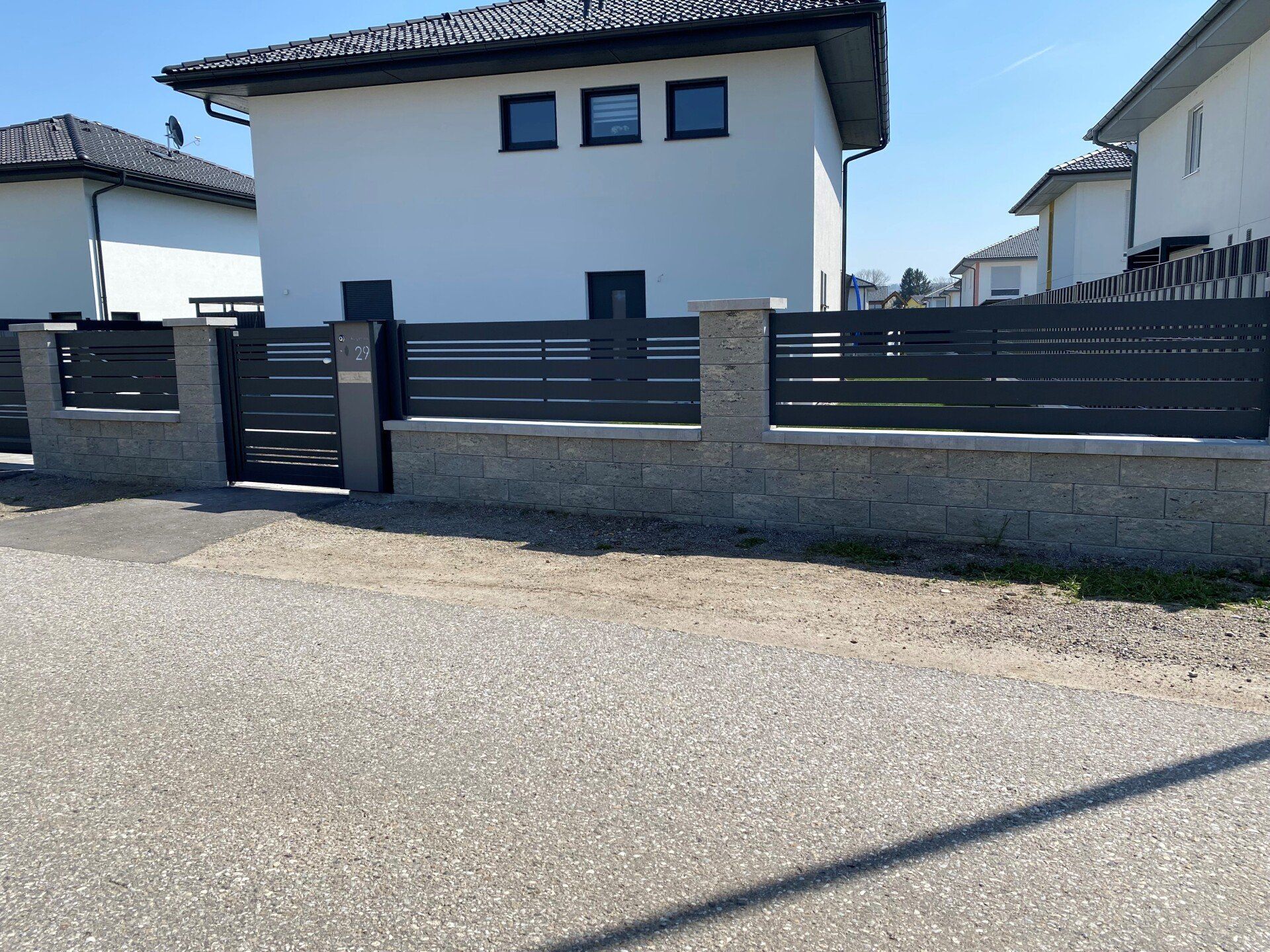 Ein weißes Haus mit einem schwarzen Zaun davor