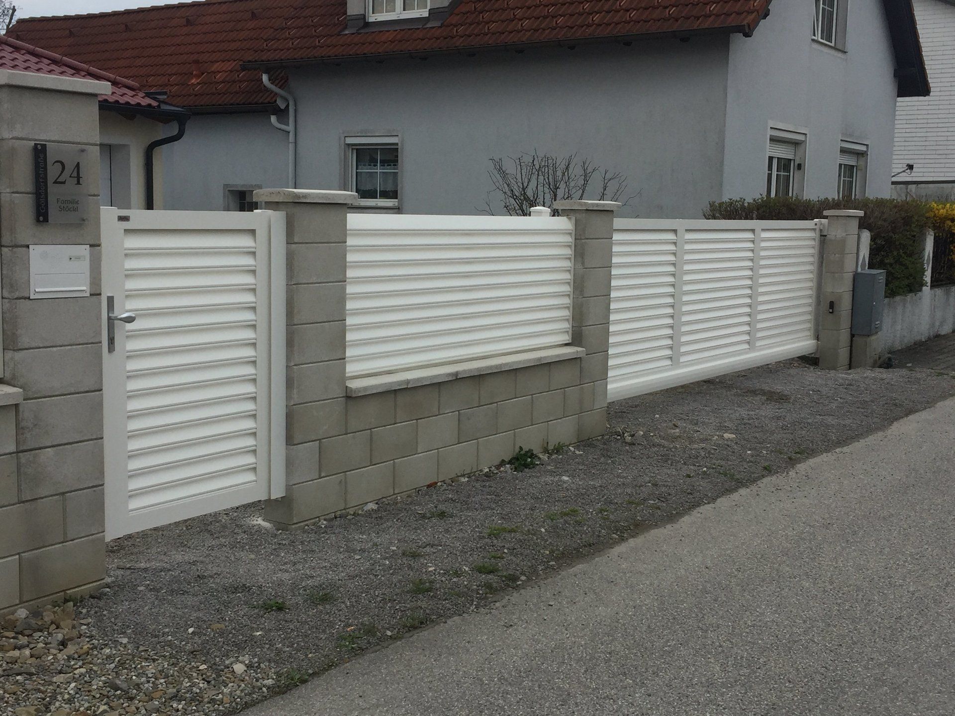 Ein weißer Zaun mit einem Tor vor einem Haus