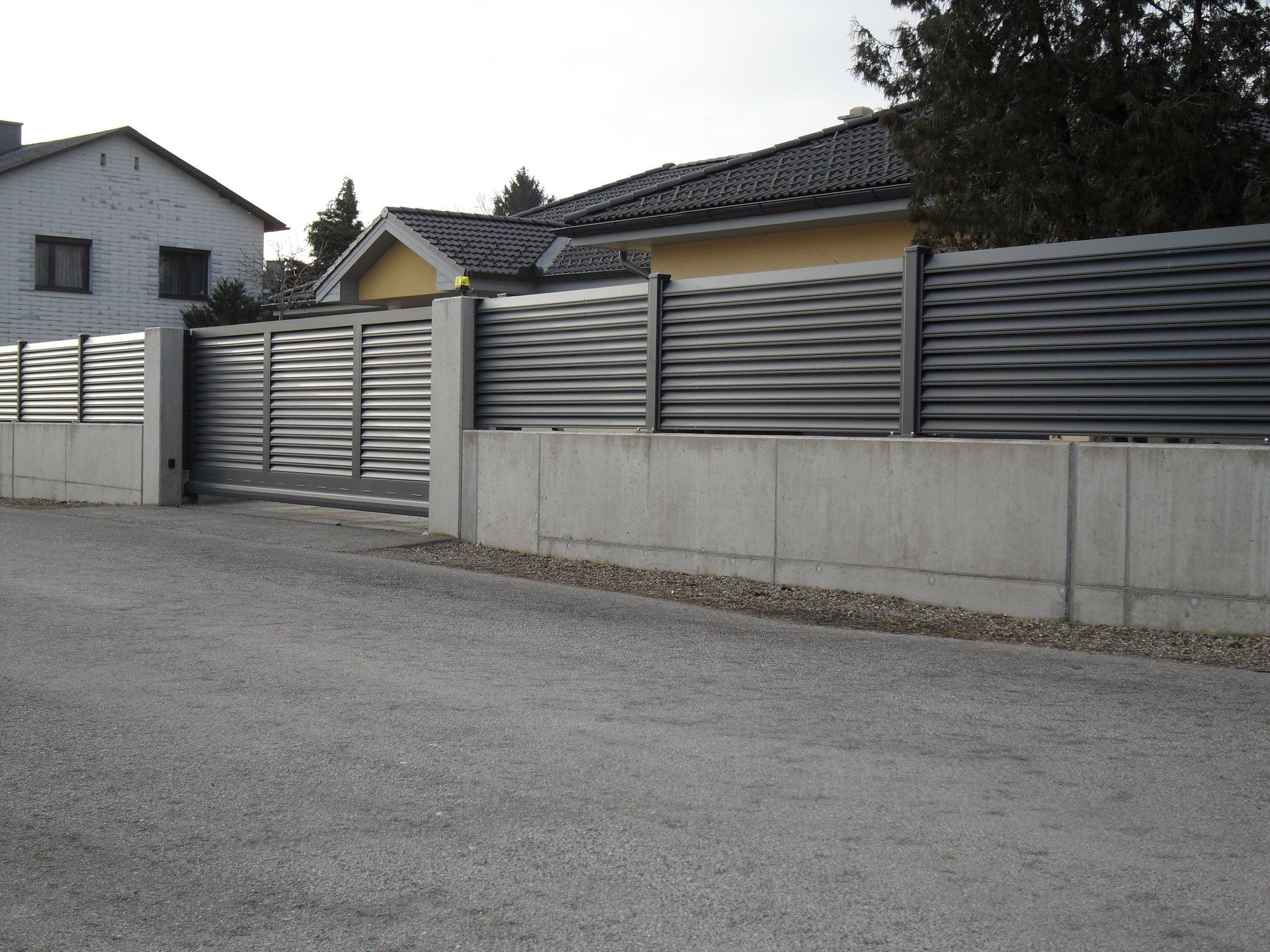 Ein Haus mit einem Zaun darum und einem Schiebetor