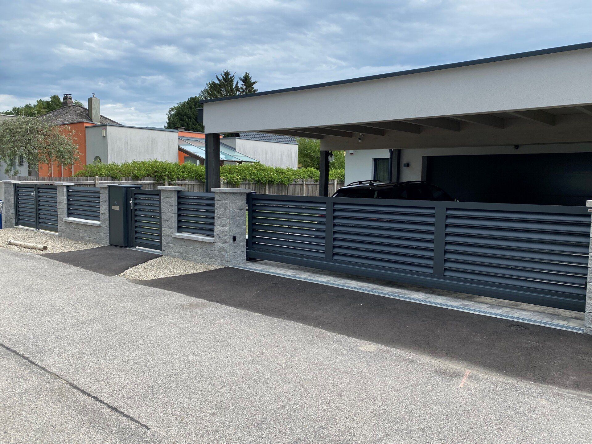 Ein Haus mit Carport und Zaun davor.
