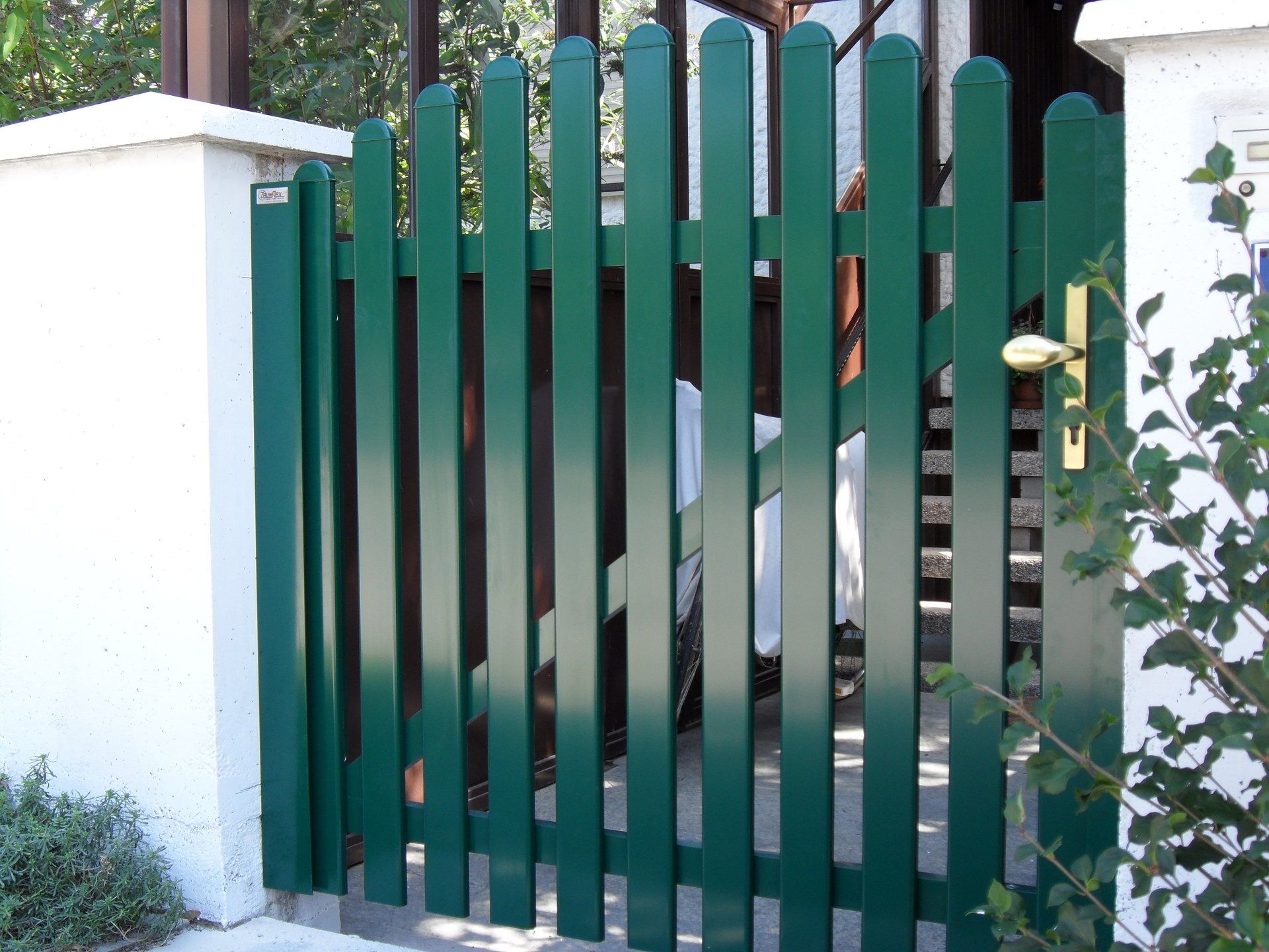Ein grüner Zaun mit einer weißen Wand dahinter