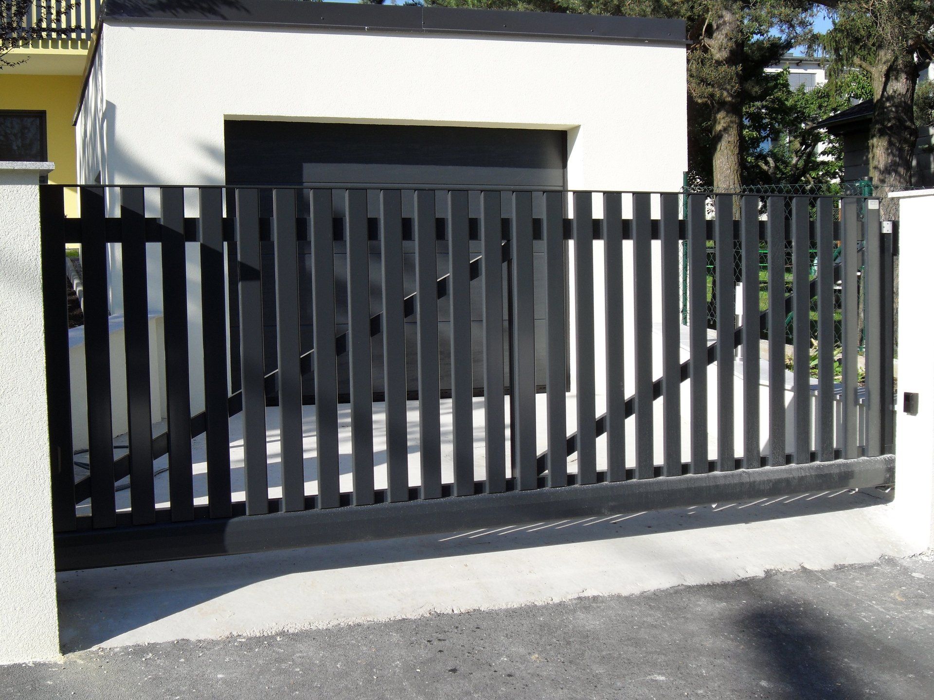 Ein schwarz-weißer Zaun mit einer Garage im Hintergrund