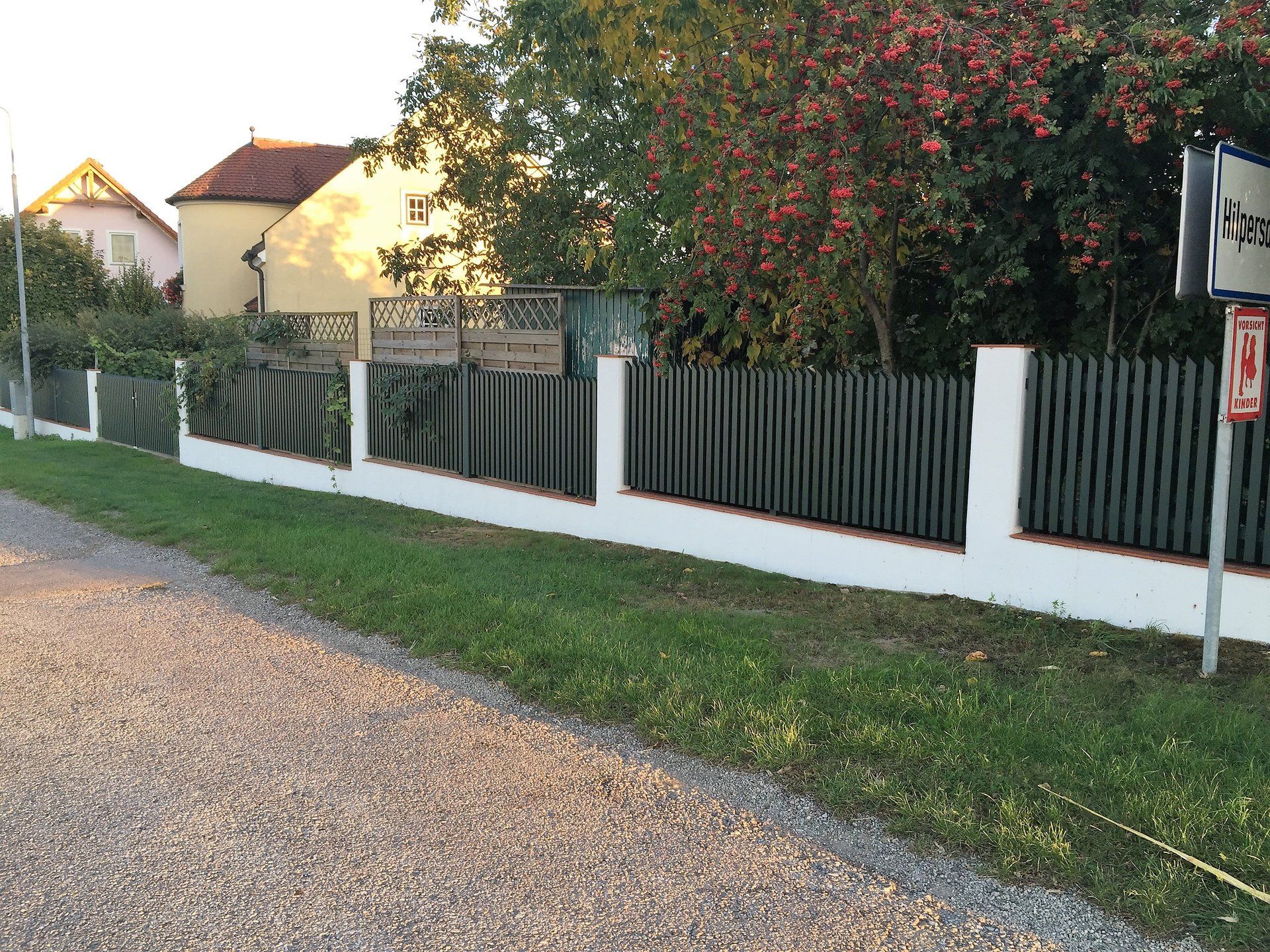 Ein Zaun entlang einer Schotterstraße mit einem Schild mit der Aufschrift „a“ darauf