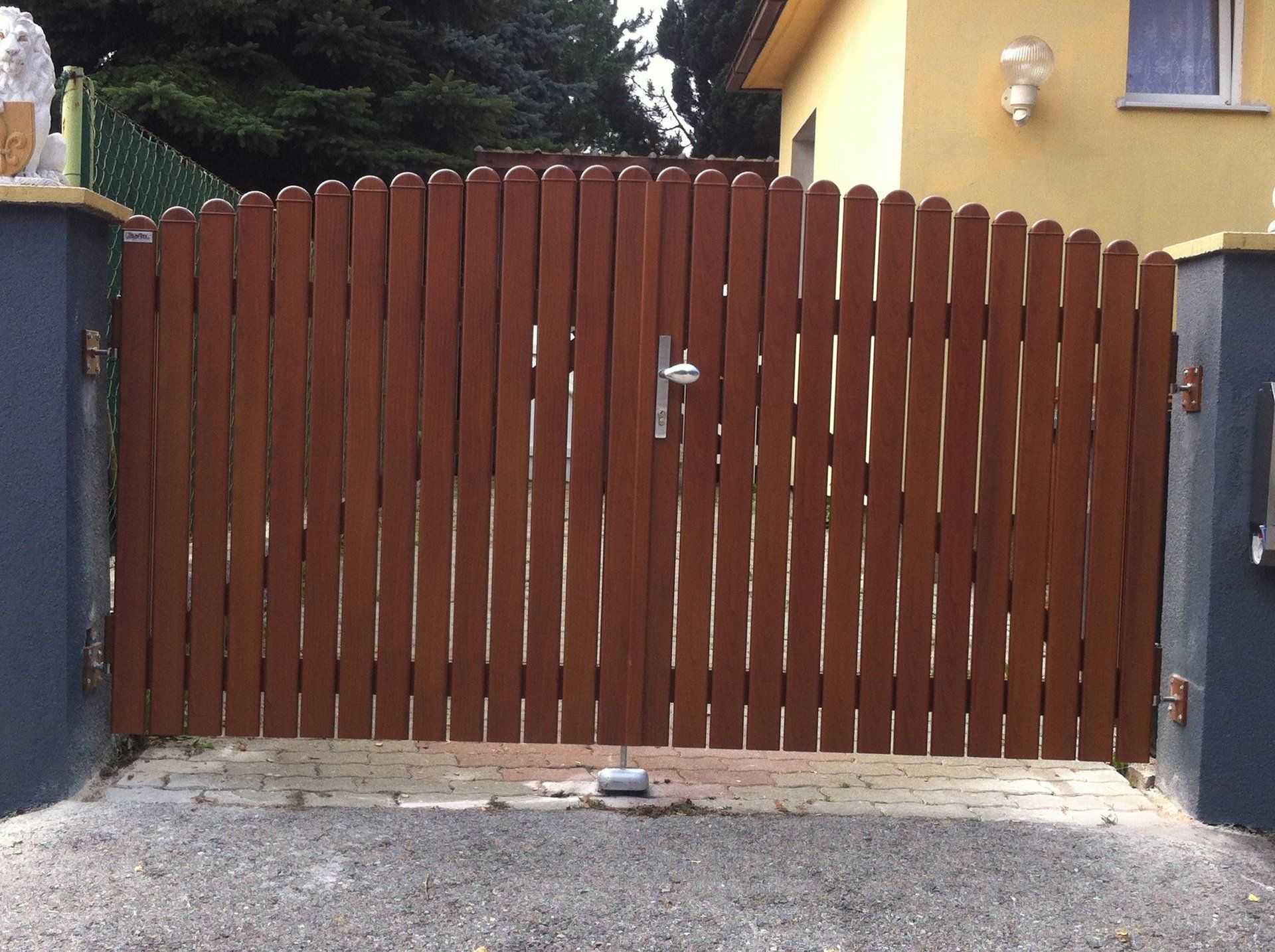 Ein Holztor ist zu einer Einfahrt vor einem gelben Haus geöffnet