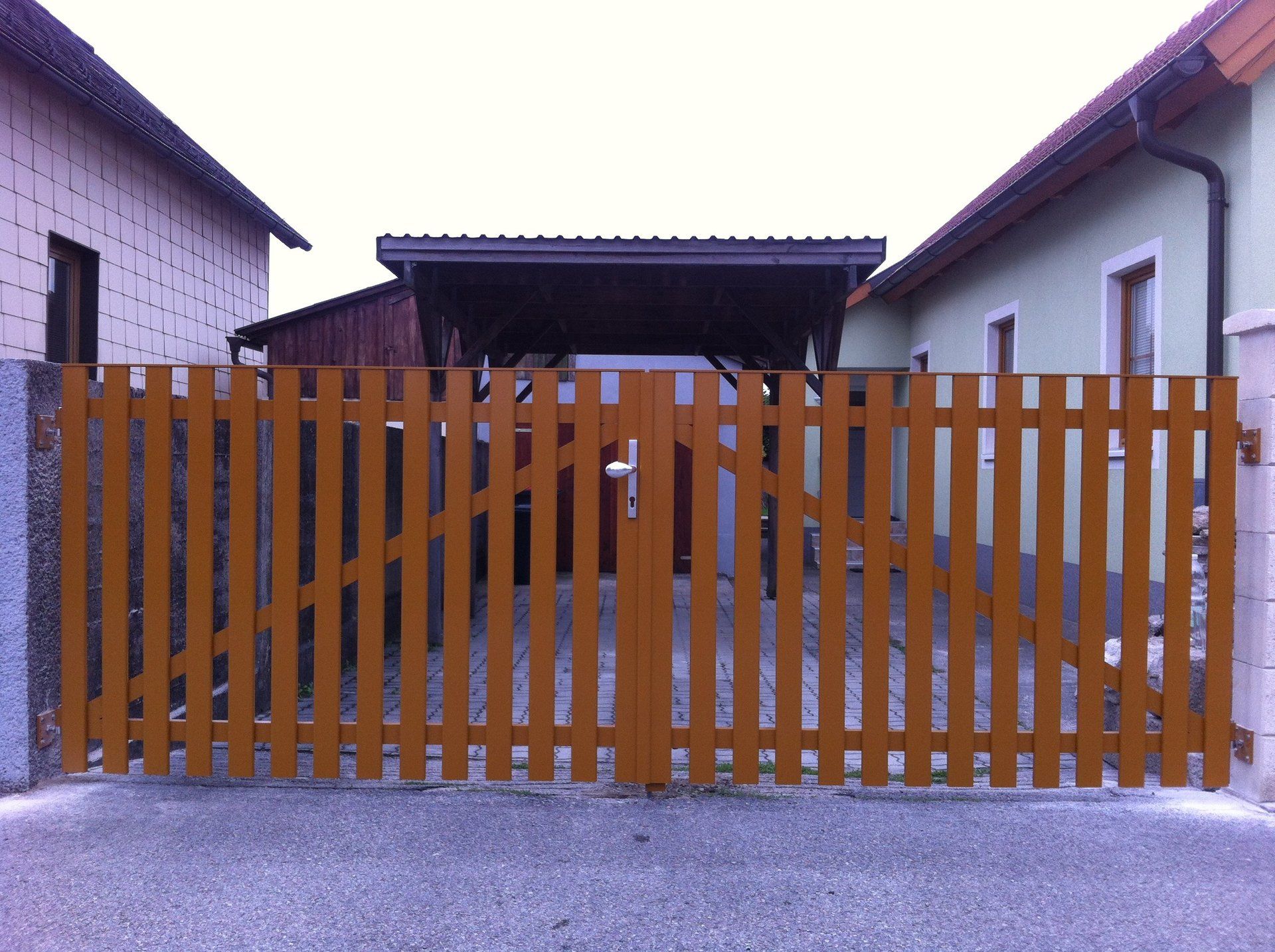 Ein Holzzaun mit einem Carport im Hintergrund