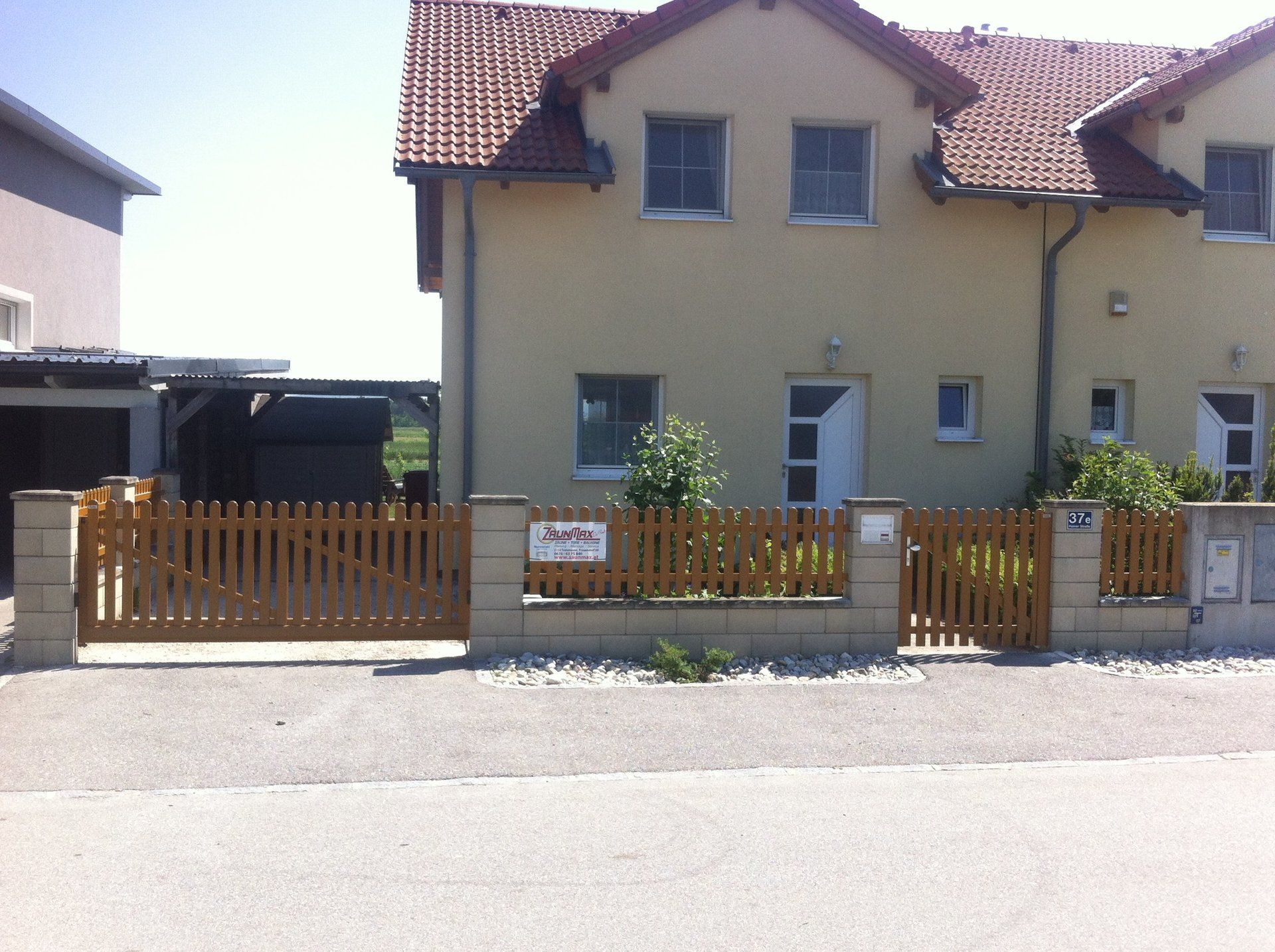 Ein Haus mit einem Holzzaun und einem Schild mit der Aufschrift „Auto“