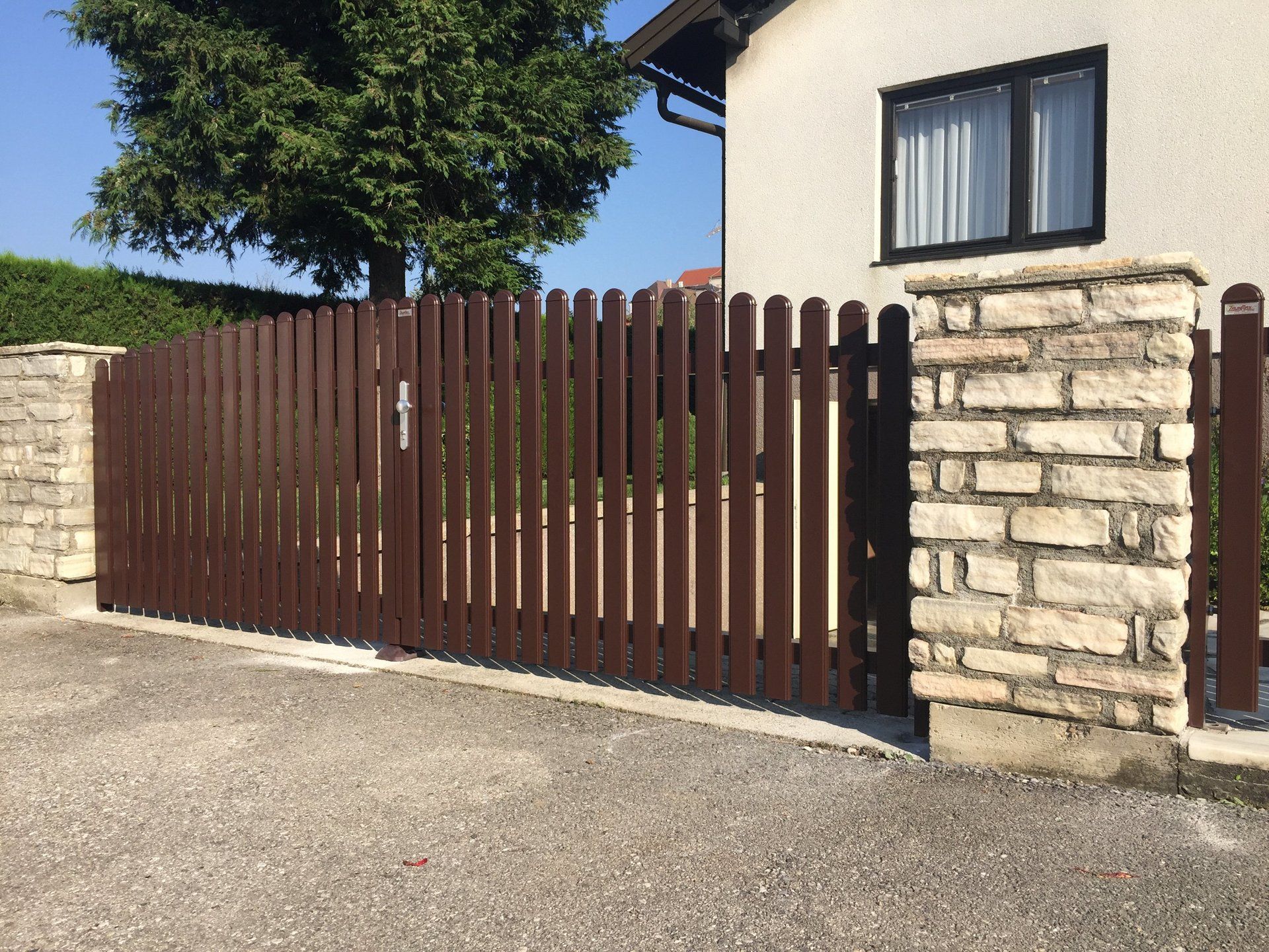 Ein Haus mit einem braunen Zaun und einer Backsteinmauer