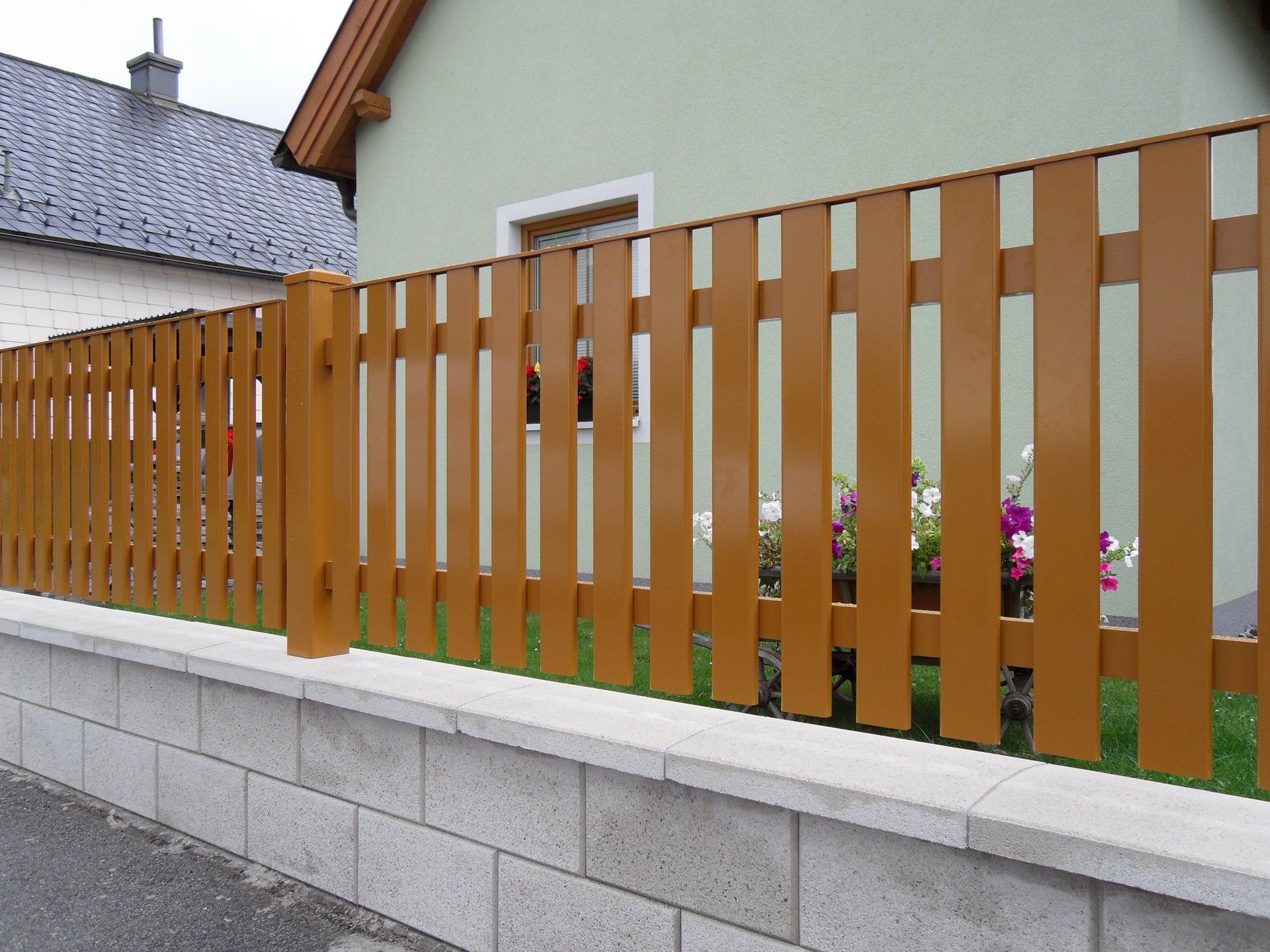 Ein Holzzaun umgibt eine Backsteinmauer vor einem Haus