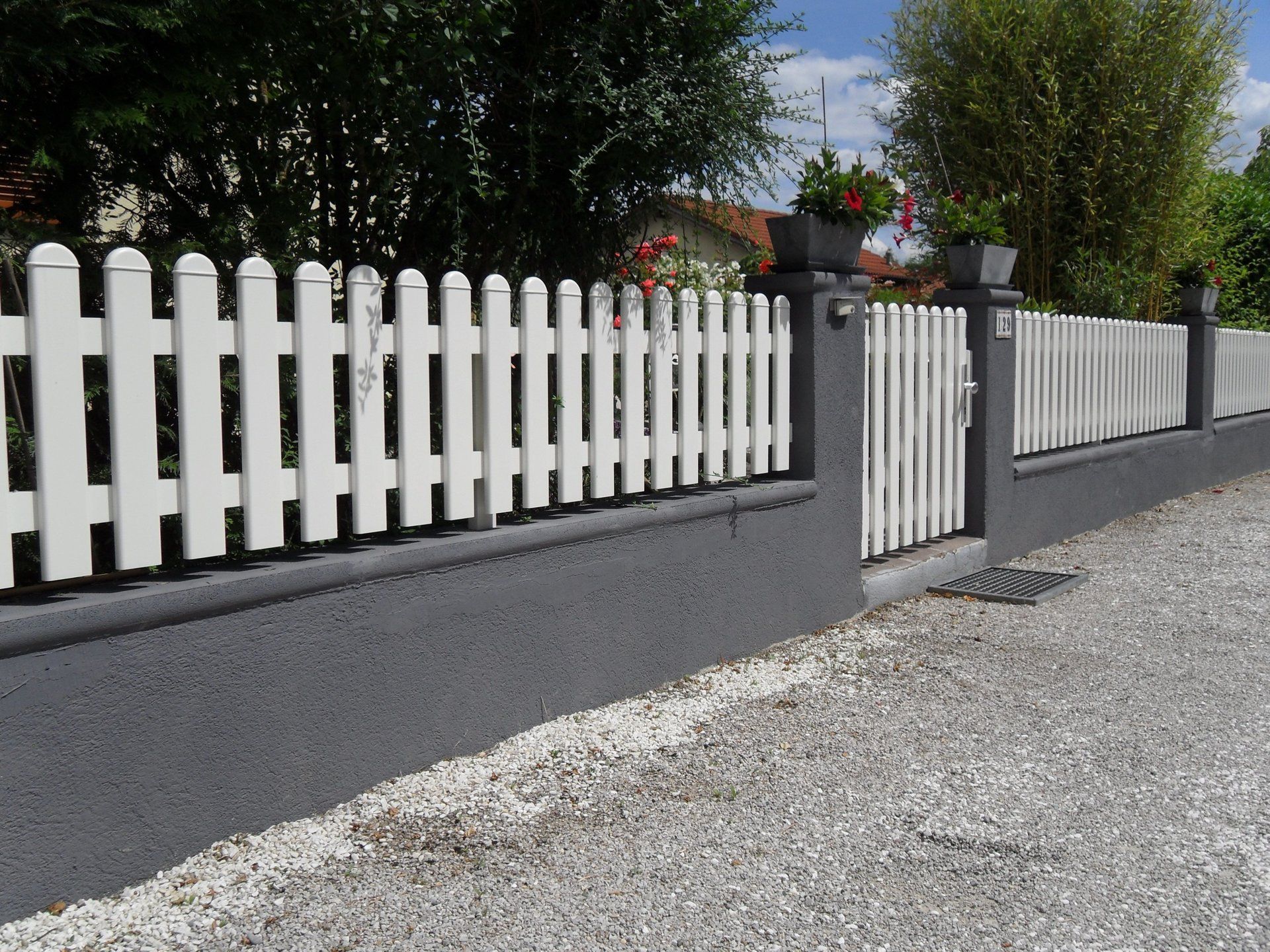 Ein weißer Lattenzaun entlang einer Schotterstraße